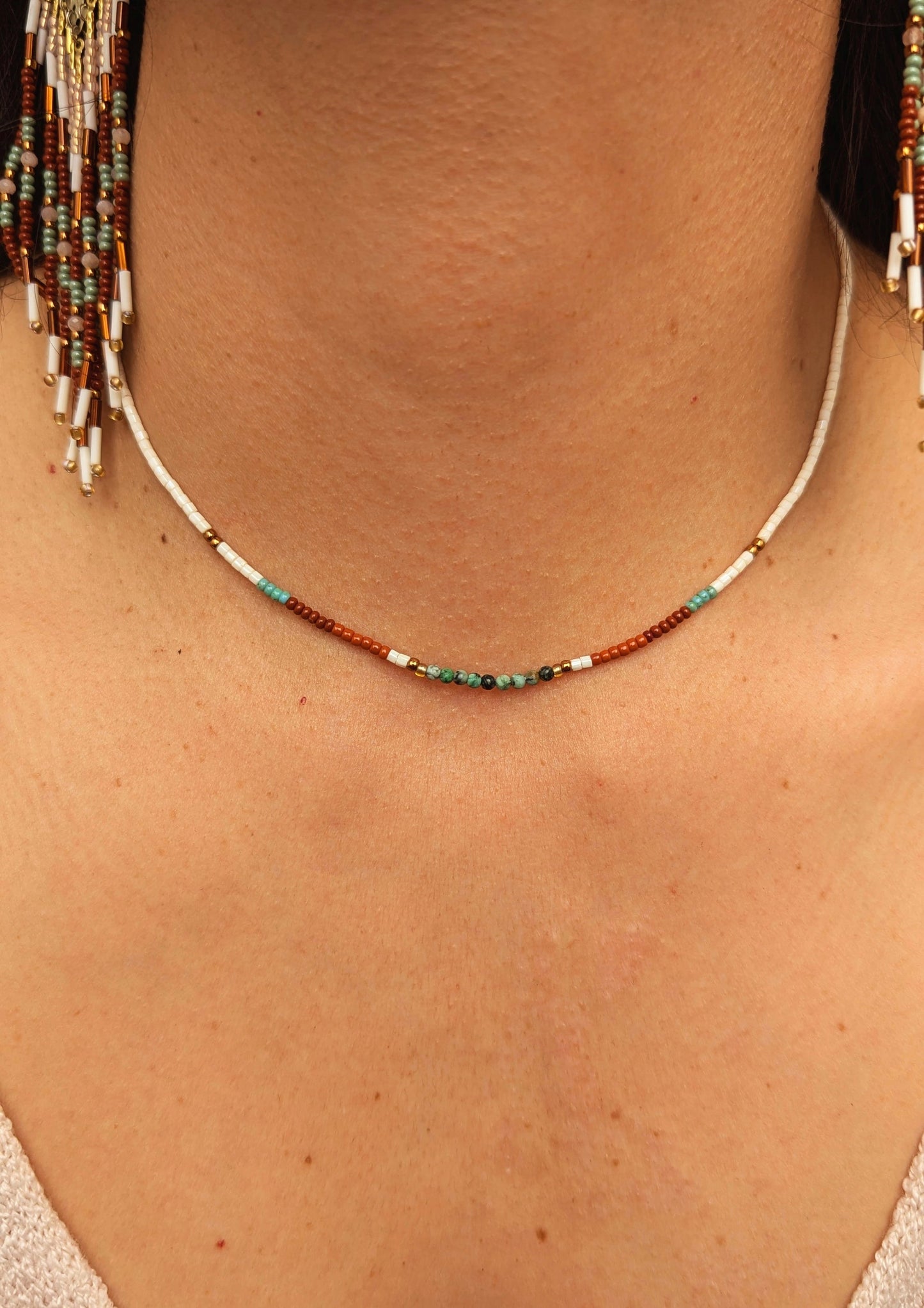 Woman wearing a handcrafted beaded choker necklace by Moon & Milk, featuring cream, terracotta, and turquoise beads. Close-up shot showcasing the intricate beadwork and boho design.