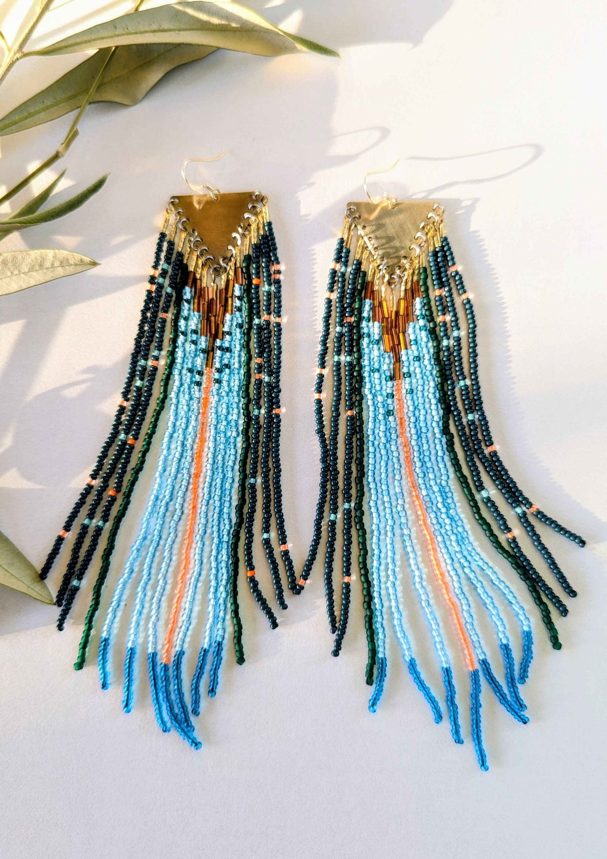 Beaded earrings with blue, green, and orange beads on a white surface.