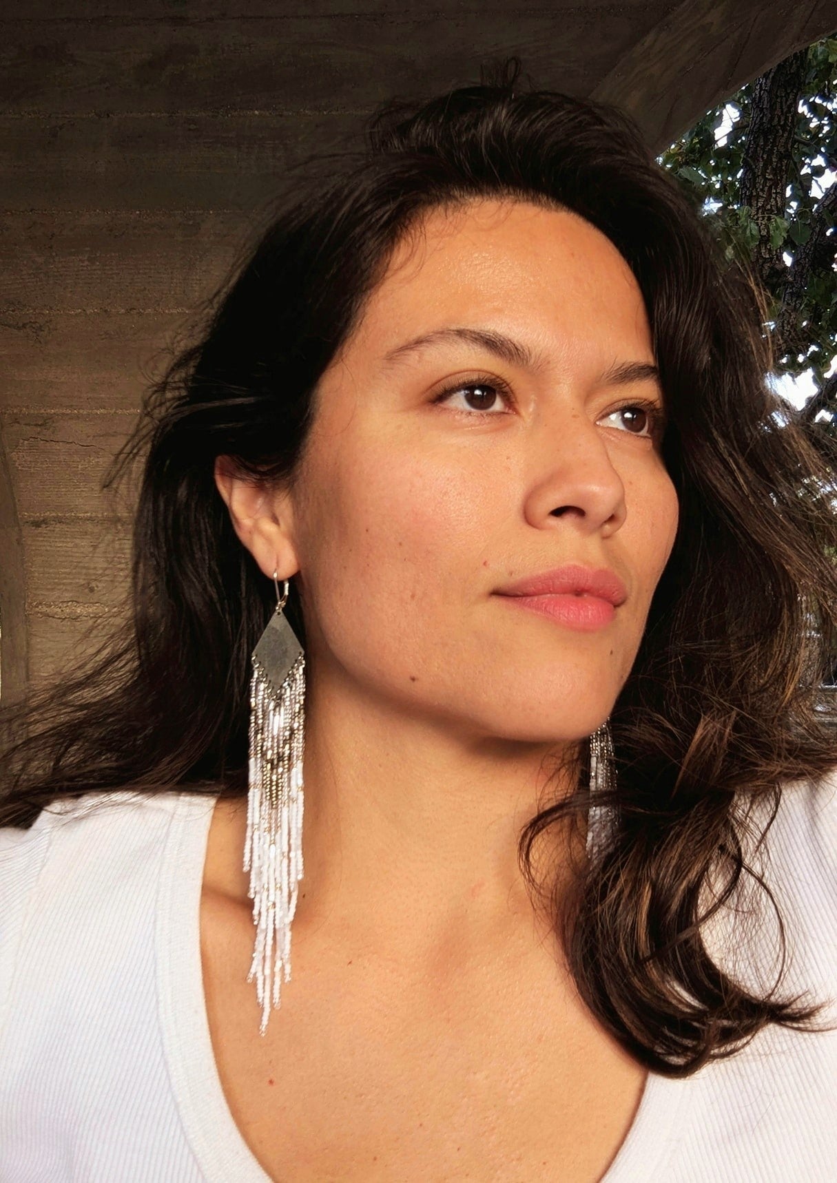 Handcrafted beaded earrings on a model with Czech beads, silver accents, and brass, featuring a delicate white and silver design for an artisan-crafted, textured look.