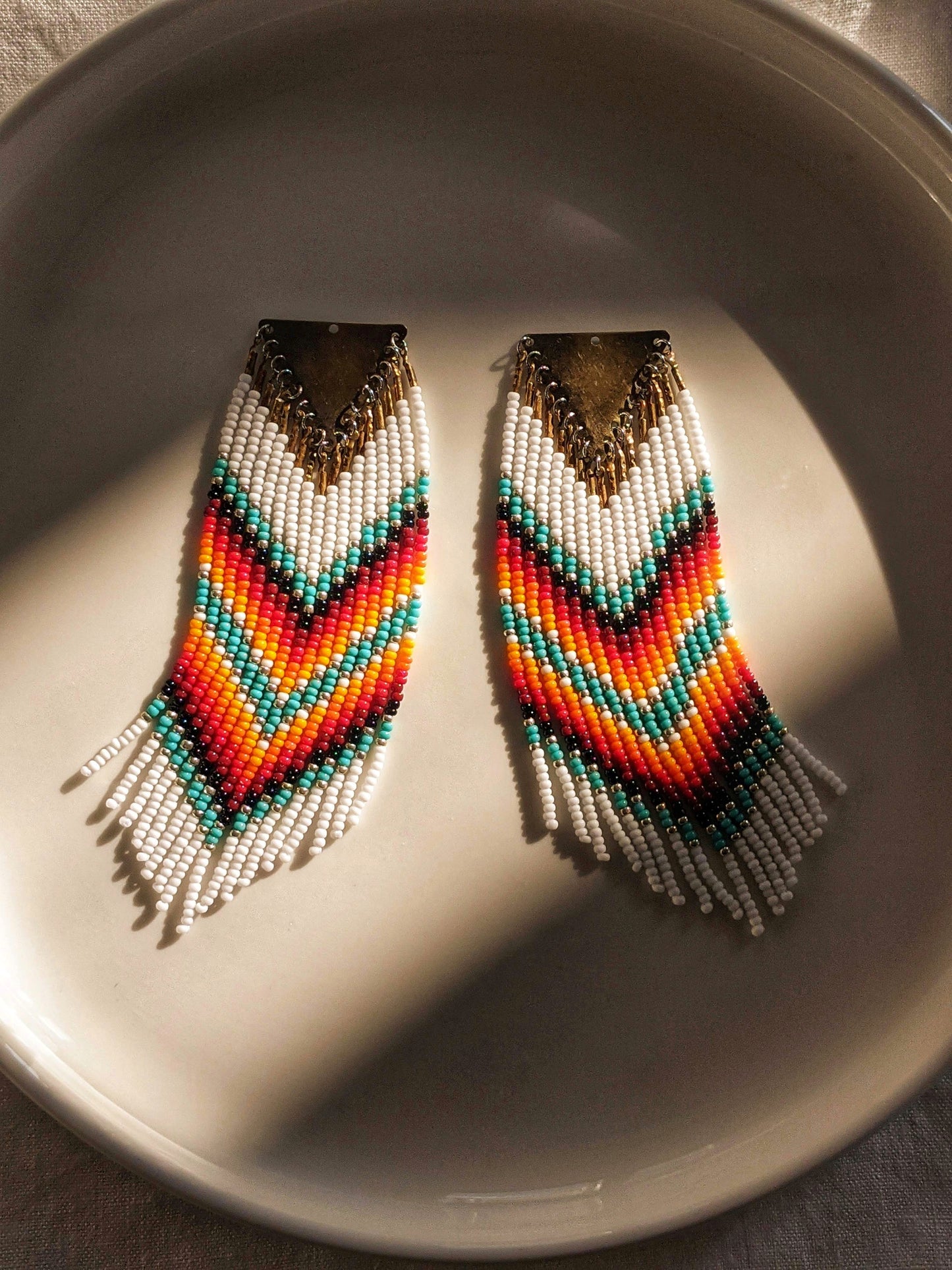 Rigoberta Classic White Native Earrings by Moon & Milk featuring vibrant red, turquoise, yellow, and white seed beads in a handwoven chevron pattern.