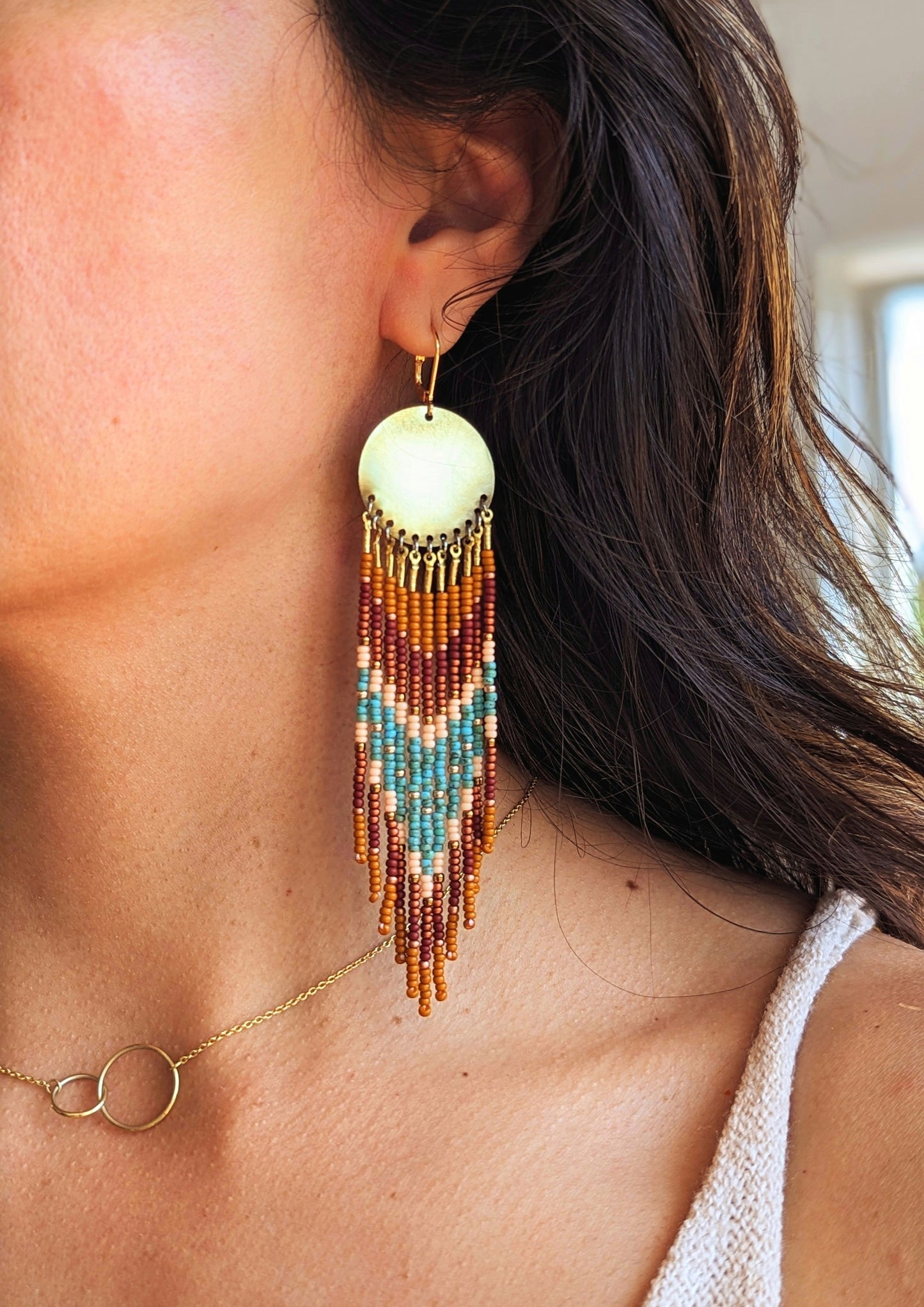 Moon & Milk handmade earrings with brown, turquoise, and peach seed beads worn by a woman.