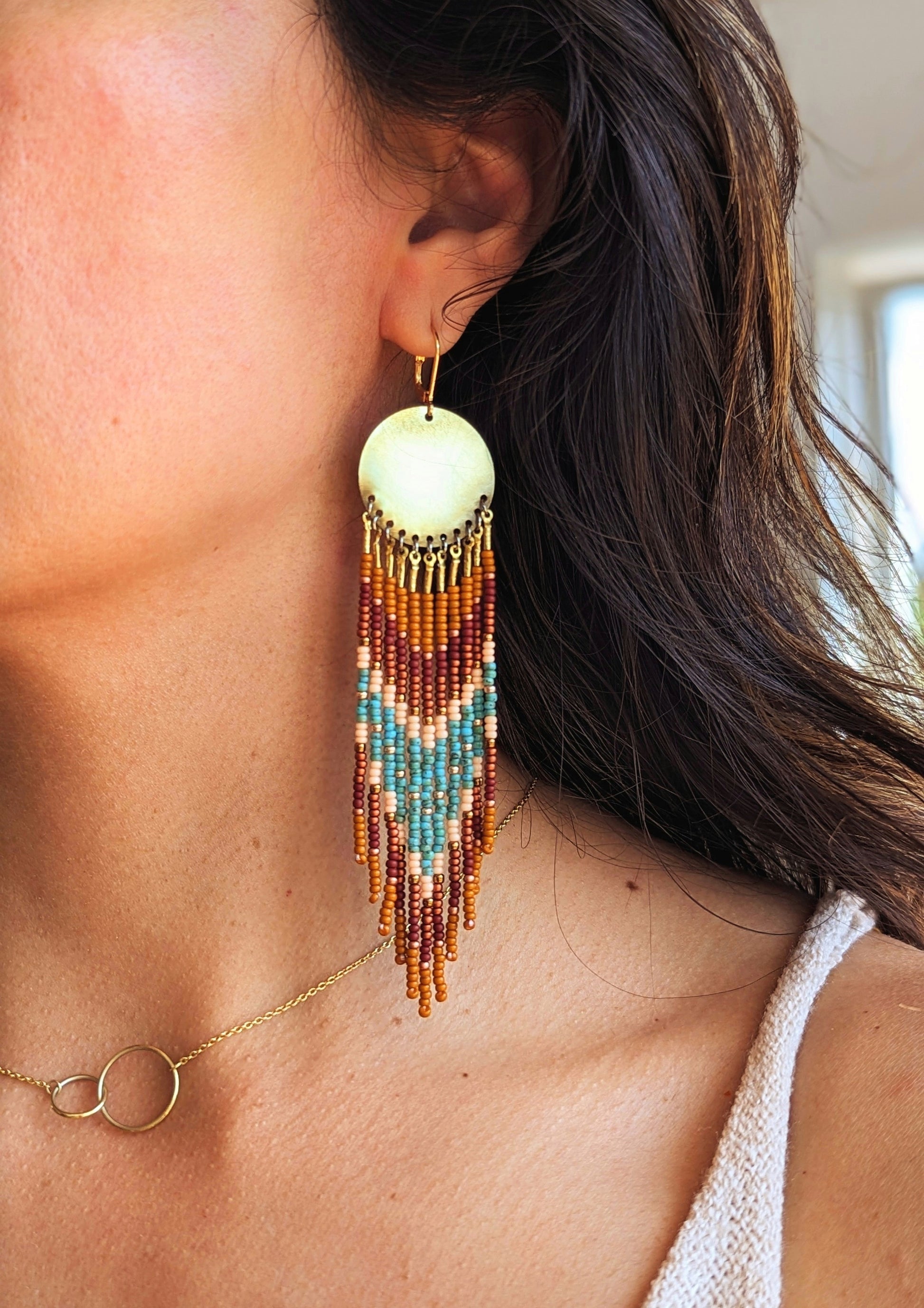 Moon & Milk handmade earrings with brown, turquoise, and peach seed beads worn by a woman.