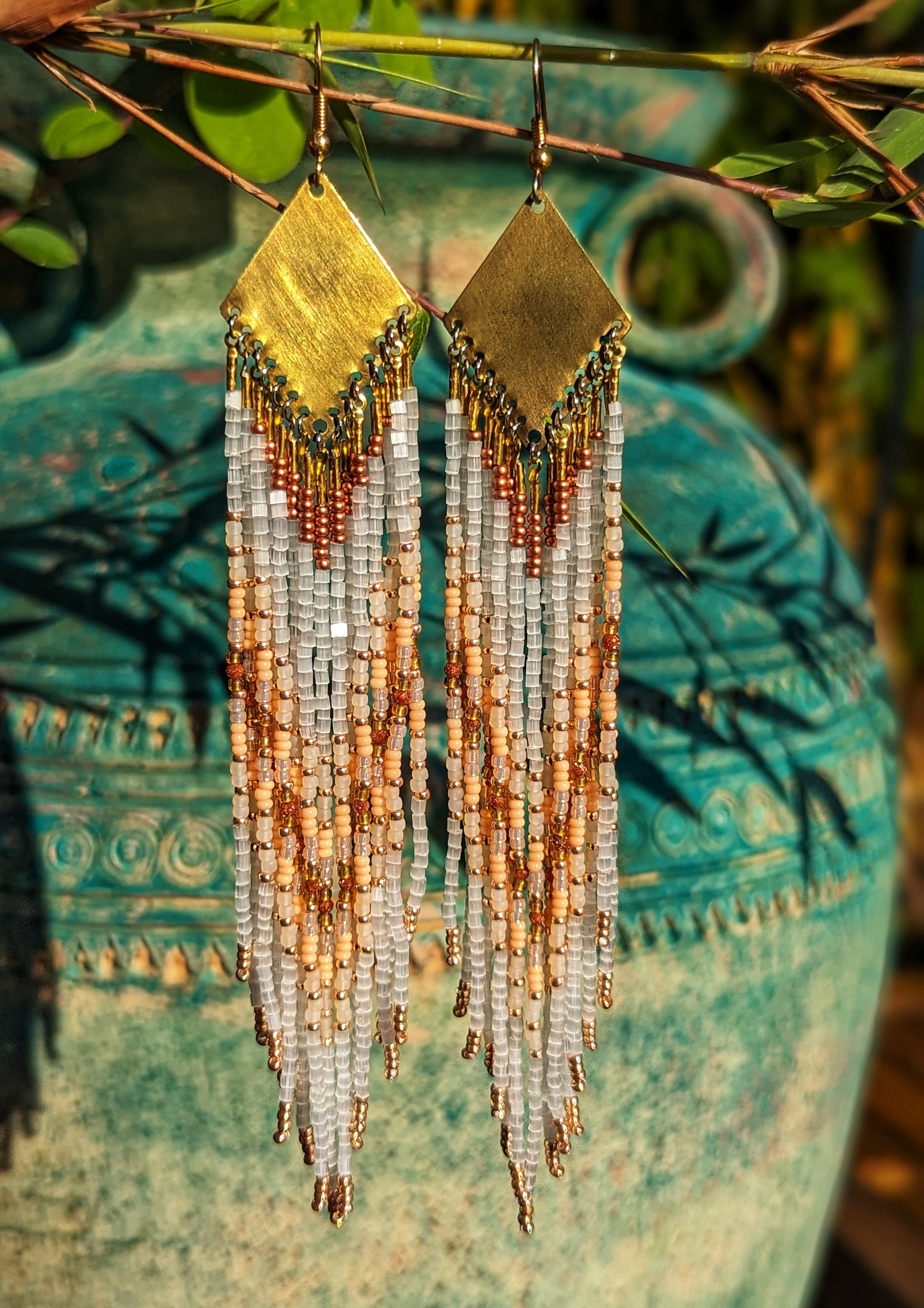 Suspended against a rustic, green background, these seed bead earrings radiate warmth and elegance. The soft hues of beige and rose gold in the beads catch the sunlight, enhancing the natural, earthy feel of this design. - Moon & Milk