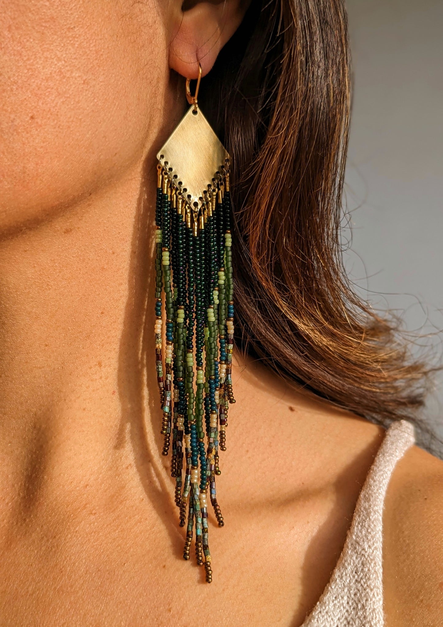 Long native beaded earrings by Moon & Milk in layered green, brown, and matte earthy tones with brass tops.