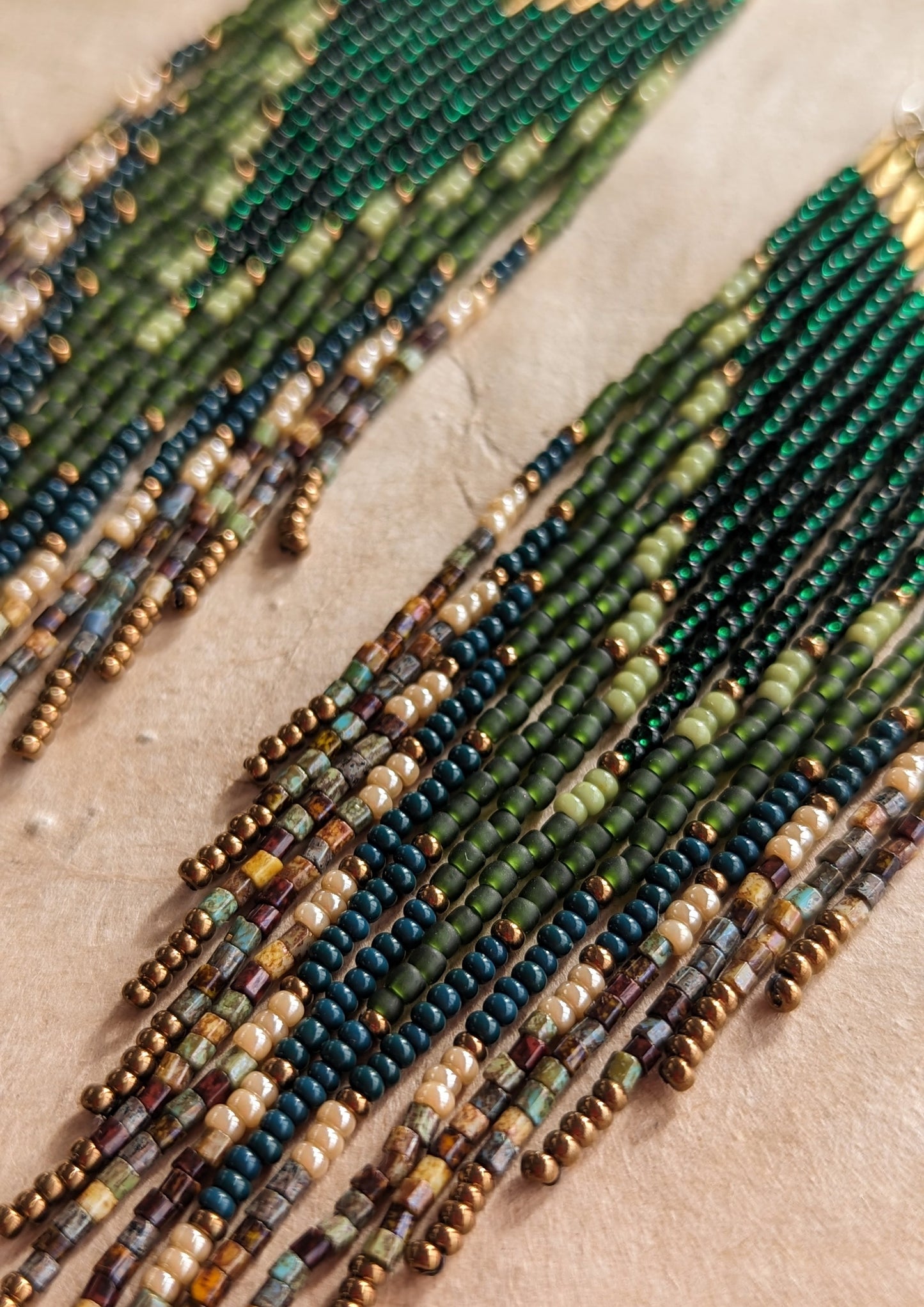 Long native beaded earrings by Moon & Milk in layered green, brown, and matte earthy tones with brass tops.