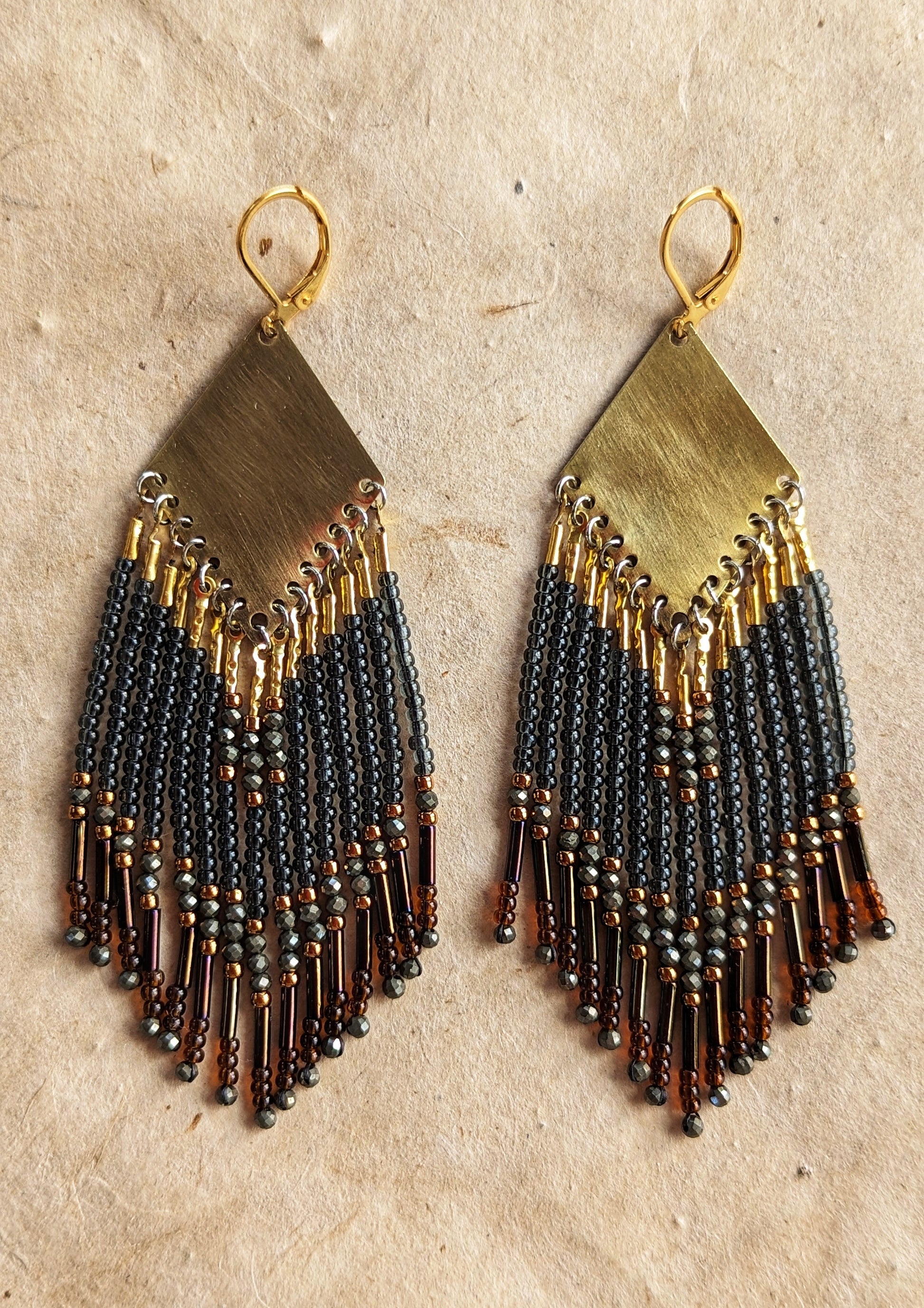 Moon & Milk handcrafted beaded earrings with black, bronze, and pyrite accents, finished with brass findings and glass bugle bead fringe.