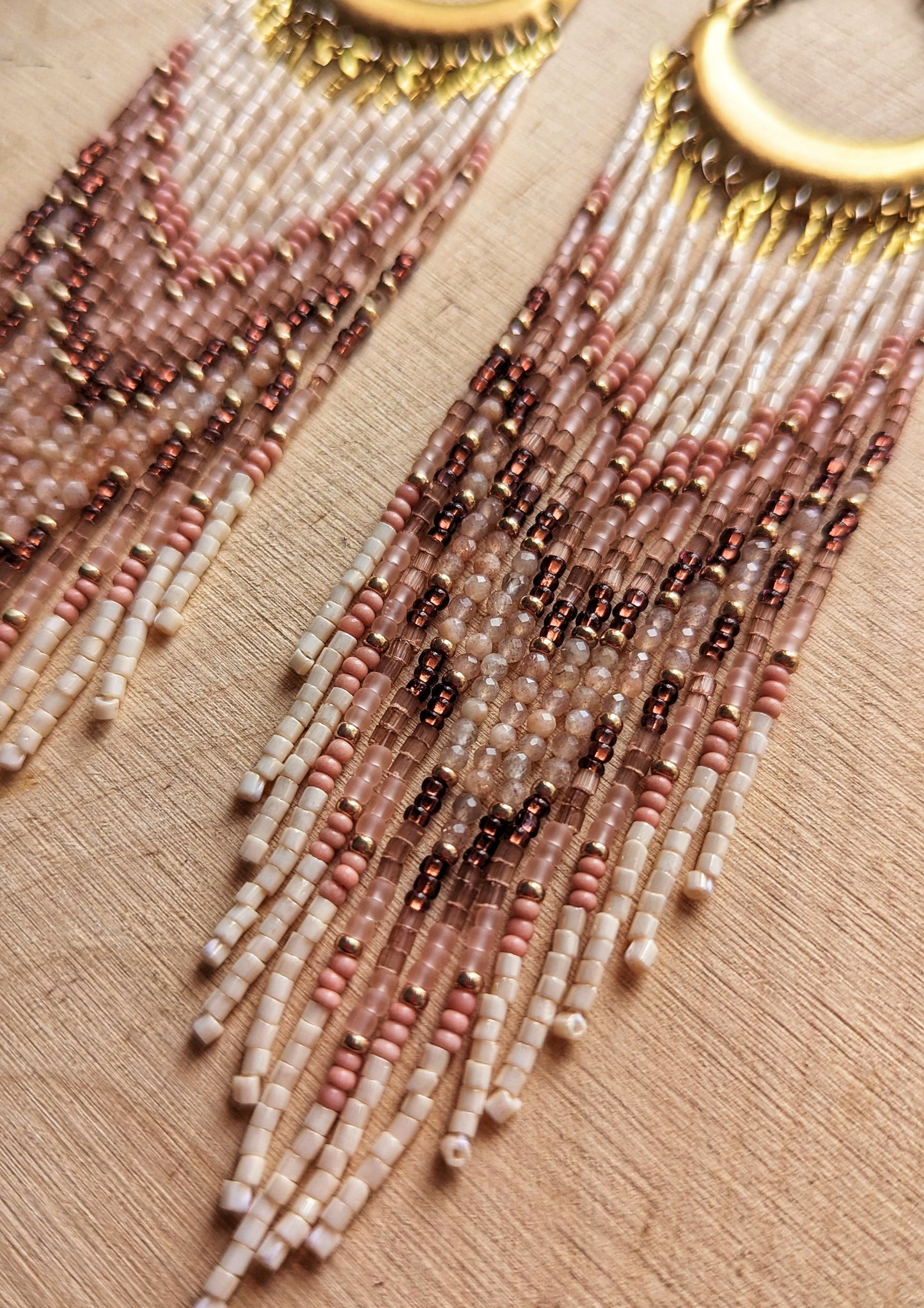 Boho-inspired beaded earrings with a brass crescent, featuring soft pink, cream, and brown beads arranged in a chevron pattern for a natural, earthy look.