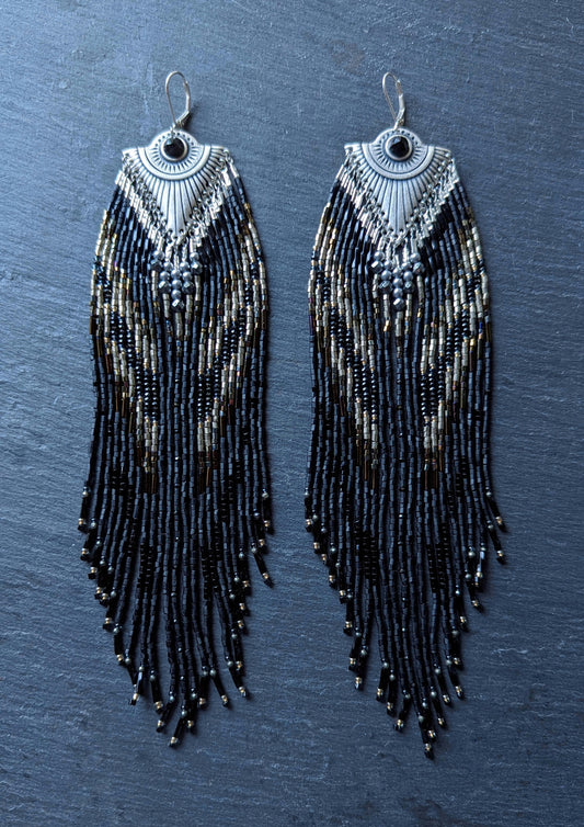 Handcrafted black beaded earrings with a fringe design. The beads feature a mix of black, silver, and gold tones, complemented by a silver fan-shaped top for an elegant, bold look