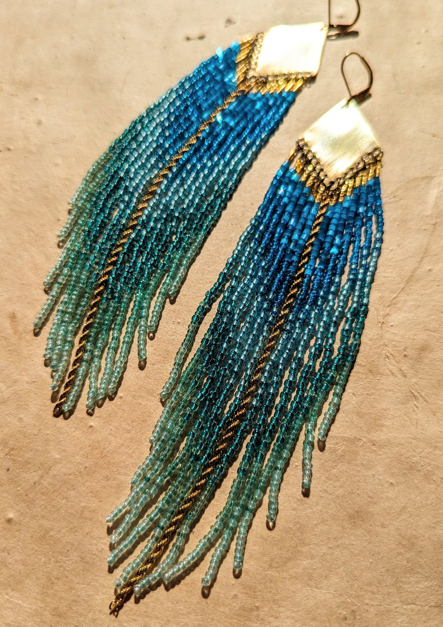 Moon & Milk - Elegant blue and turquoise beaded fringe earrings with a brass plate, featuring intricate details and cascading strands for a bold, ocean-inspired look.