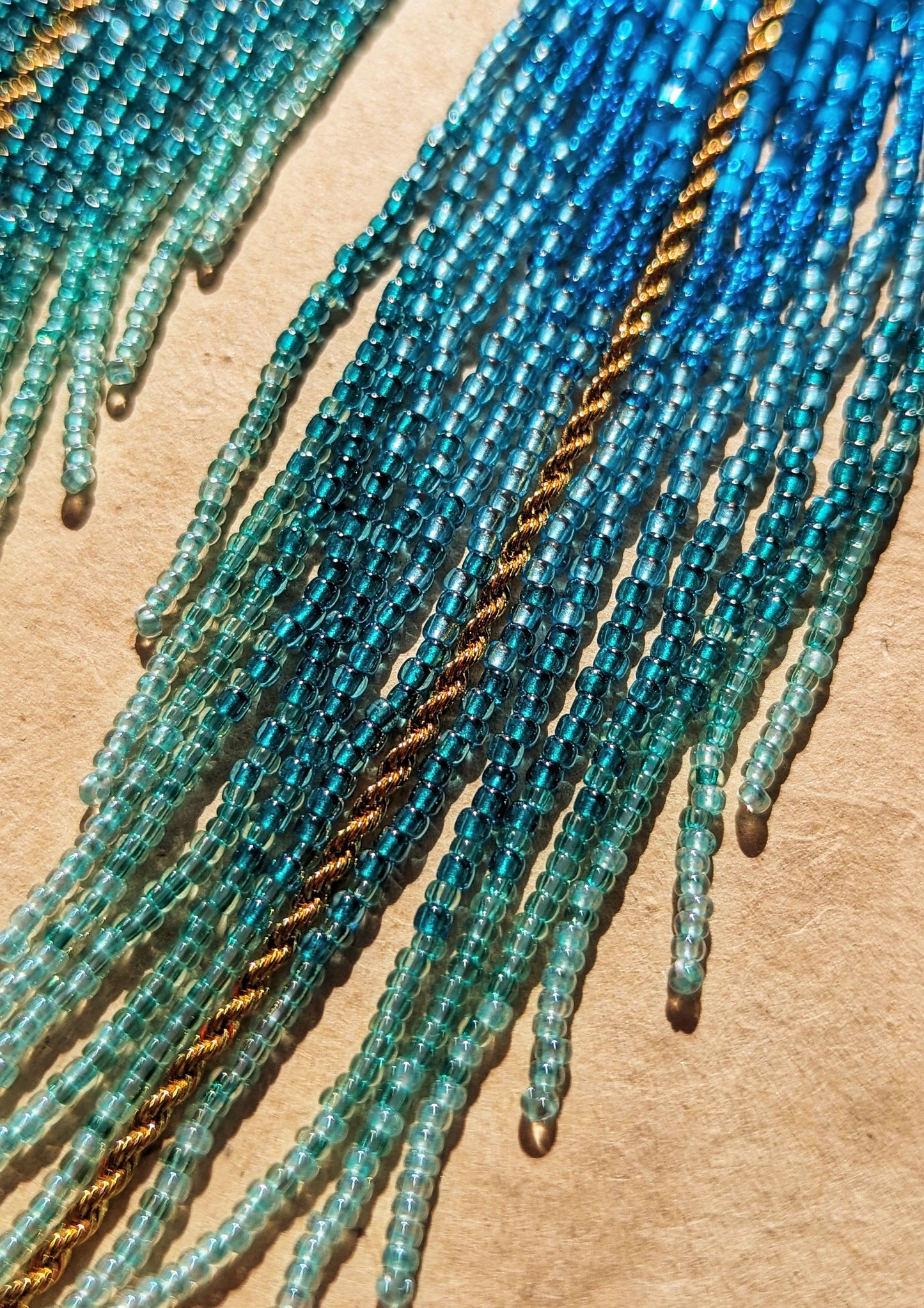 Moon & Milk - Elegant blue and turquoise beaded fringe earrings with a brass plate, featuring intricate details and cascading strands for a bold, ocean-inspired look.