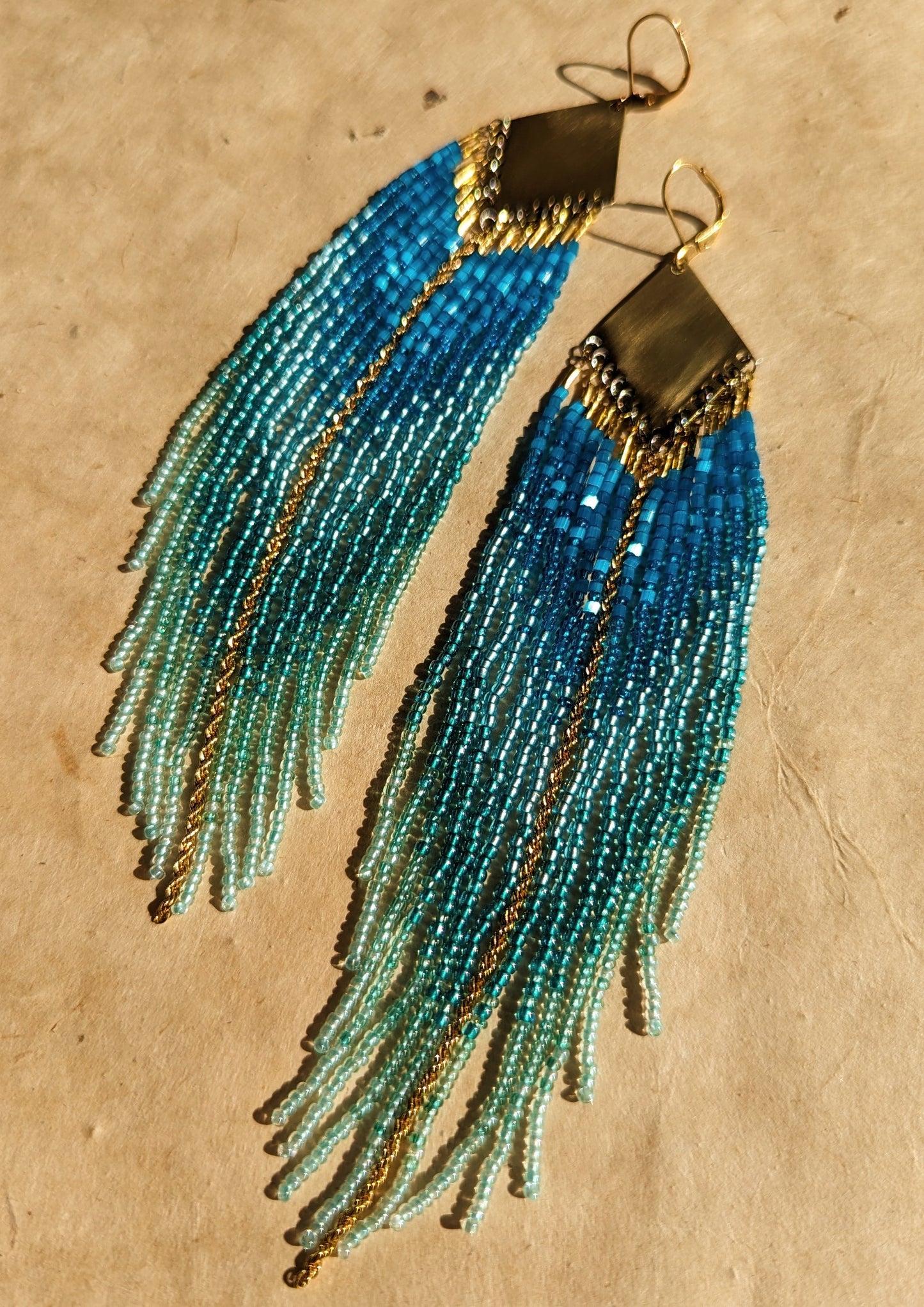 Moon & Milk - Elegant blue and turquoise beaded fringe earrings with a brass plate, featuring intricate details and cascading strands for a bold, ocean-inspired look.