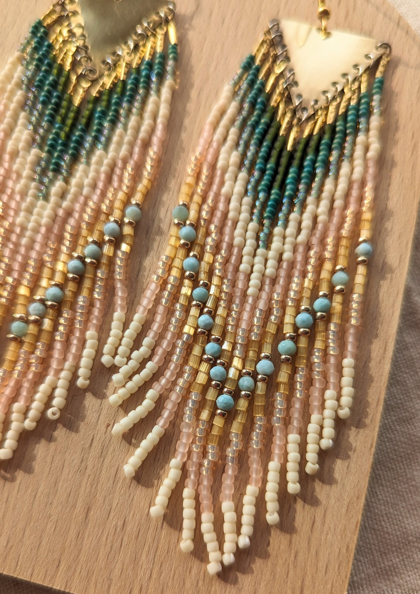 Long beaded earrings by Moon & Milk with soft pink, ivory, forest green, and sky blue larimar stones, finished with brass tops and handmade fringe design.