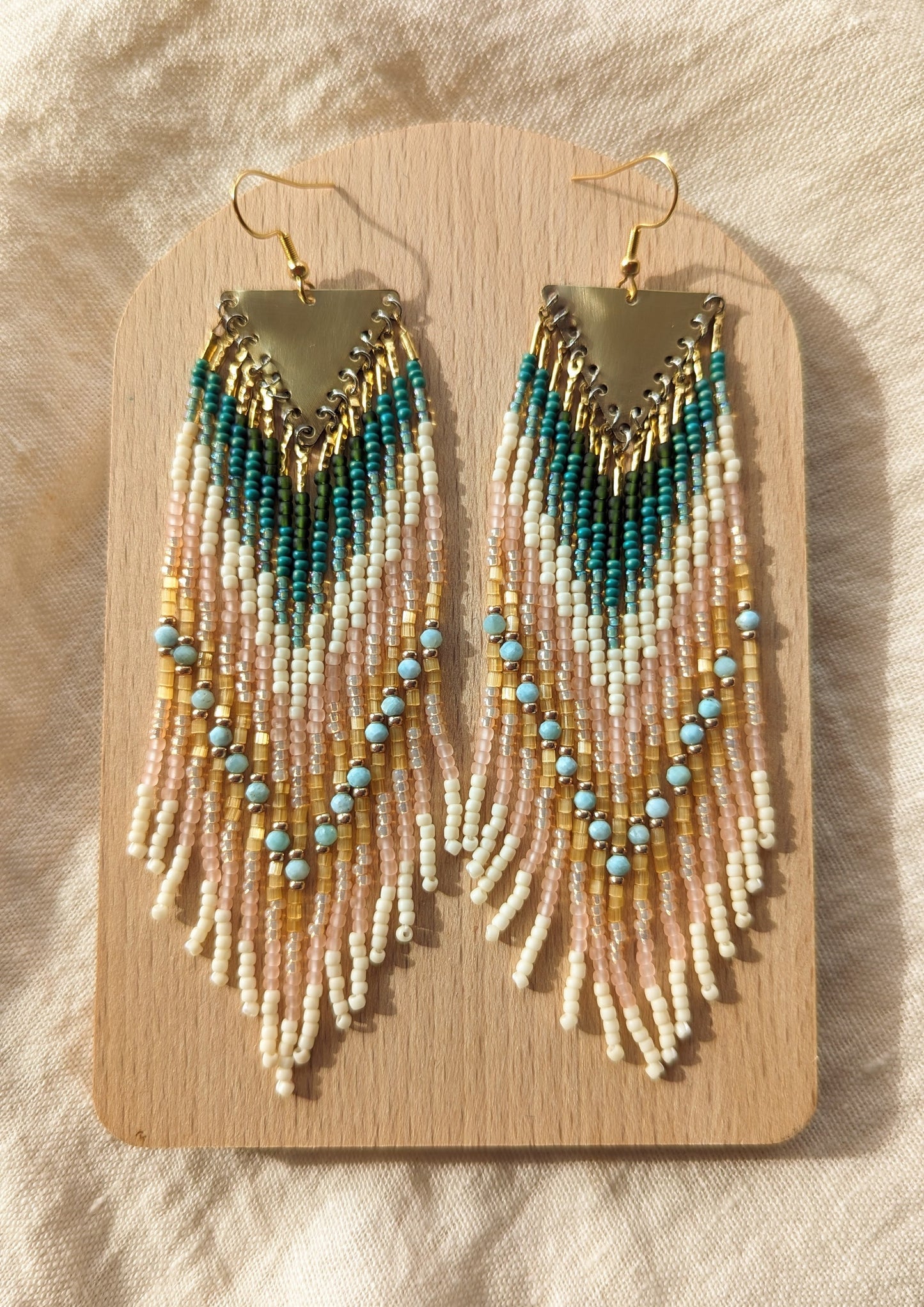 Long beaded earrings by Moon & Milk with soft pink, ivory, forest green, and sky blue larimar stones, finished with brass tops and handmade fringe design.