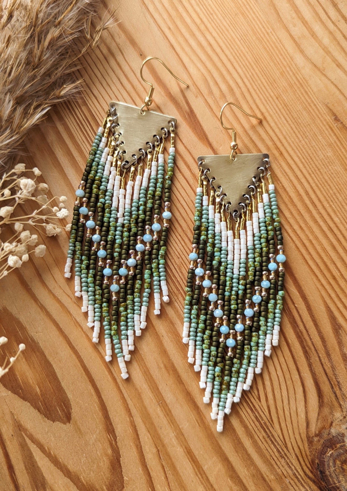 Moon & Milk green beaded earrings with ivory fringe and light blue stones, finished with brass triangles and inspired by earthy artisan beadwork.