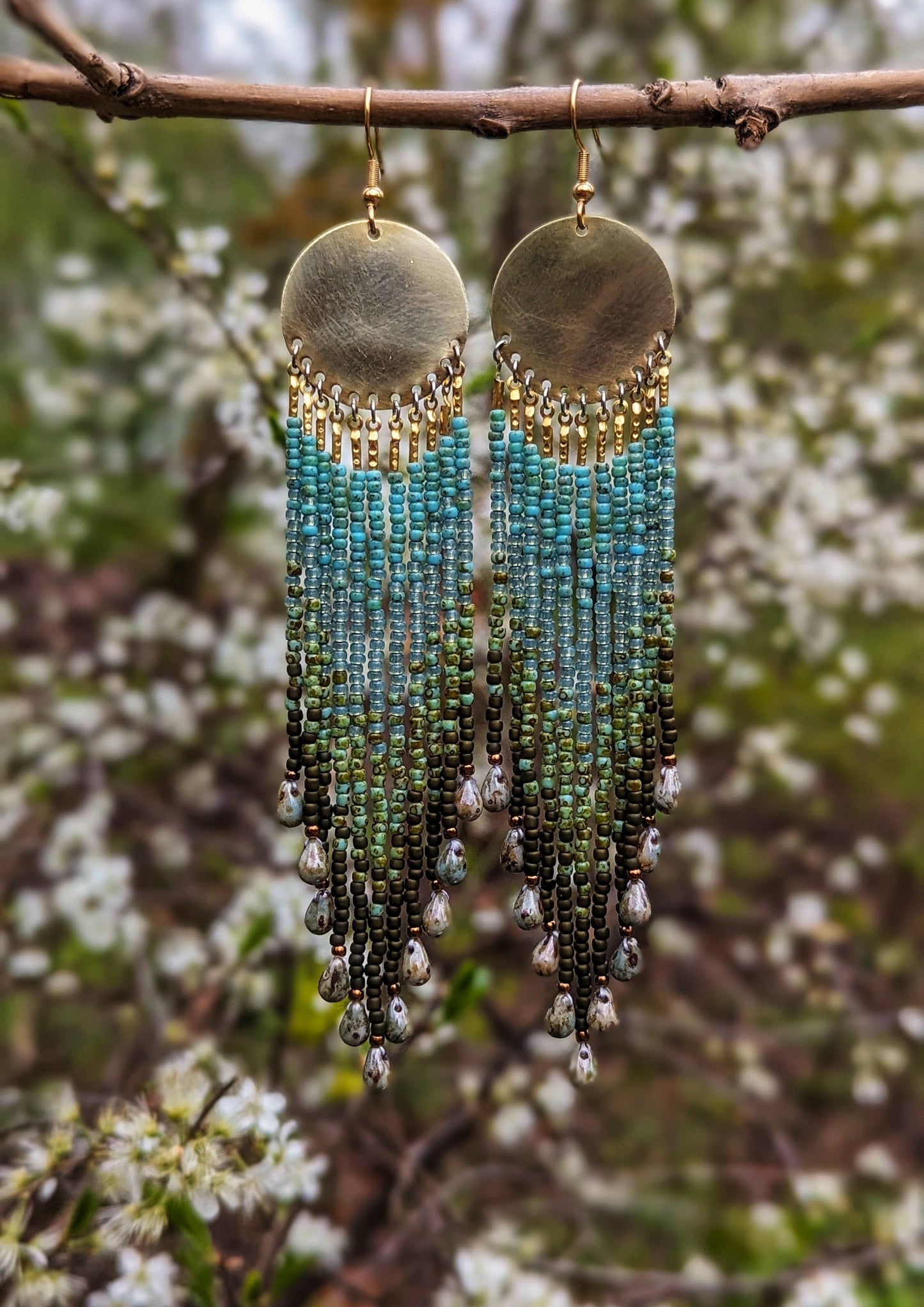 Moon & Milk long green ombré beaded earrings with brass circles and teardrop ends, handcrafted to echo forest textures and artisan beadwork style.