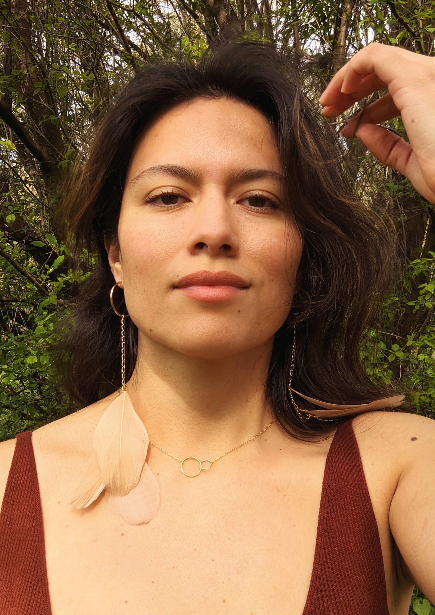 Model wearing long blush feather earrings with gold hoops and chain, Moon & Milk design, photographed outdoors in natural light.