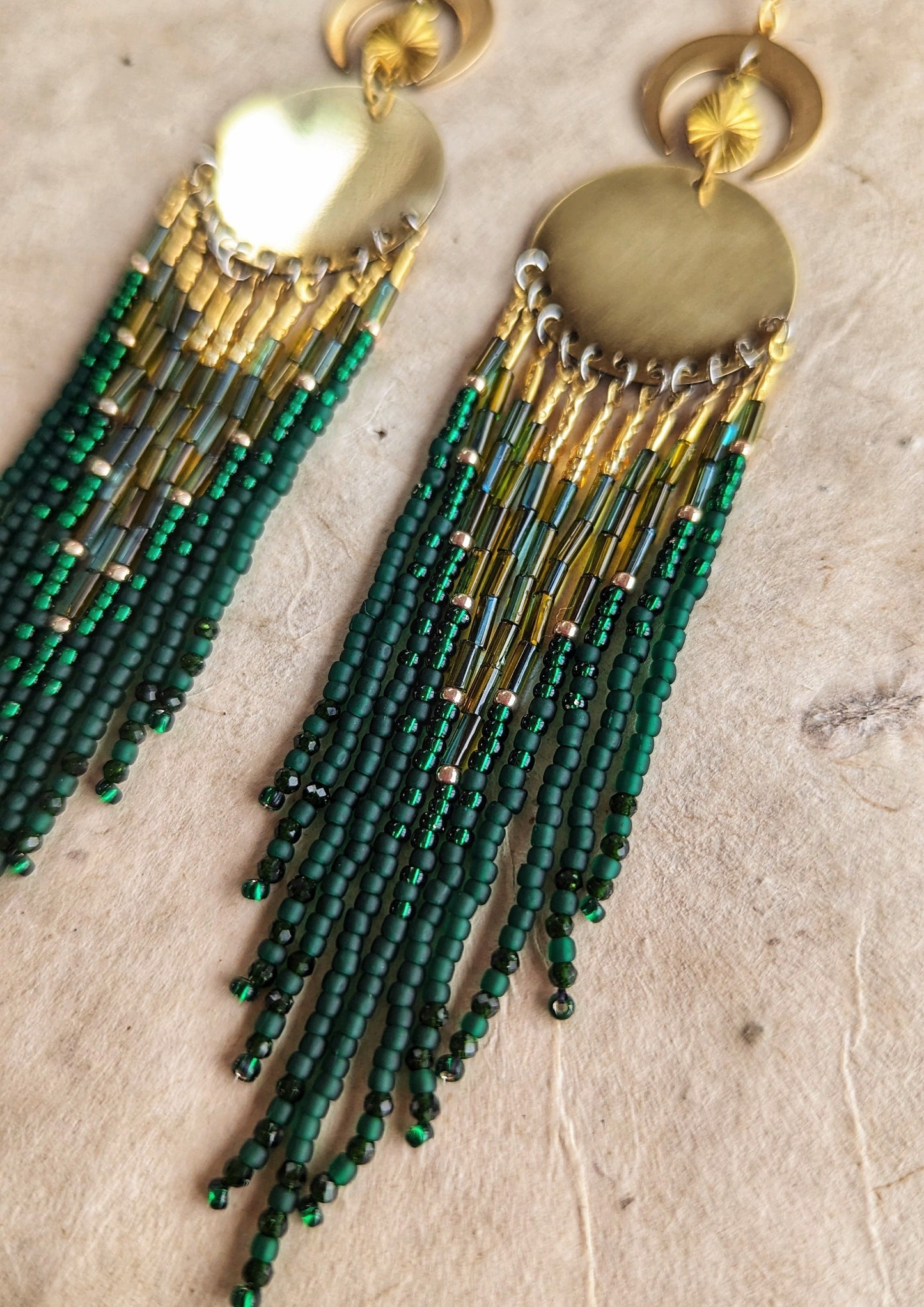 Brass statement earrings with green and gold beaded fringe, featuring a round centerpiece and crescent moon details. - Moon & Milk
