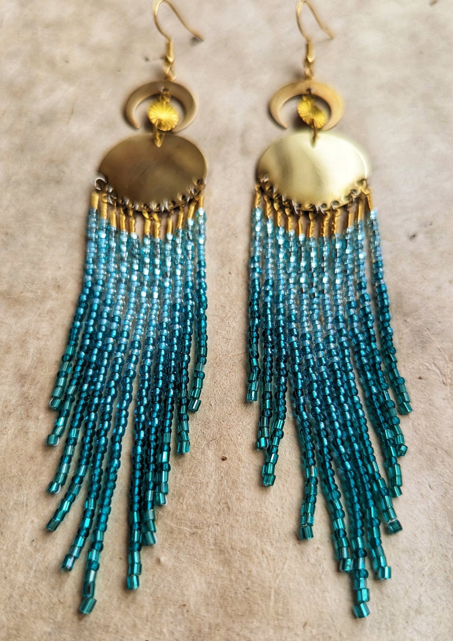 Handcrafted aqua beaded earrings by Moon & Milk, featuring cascading glass beads in shades of blue and brass accents, reflecting the beauty of the sea.