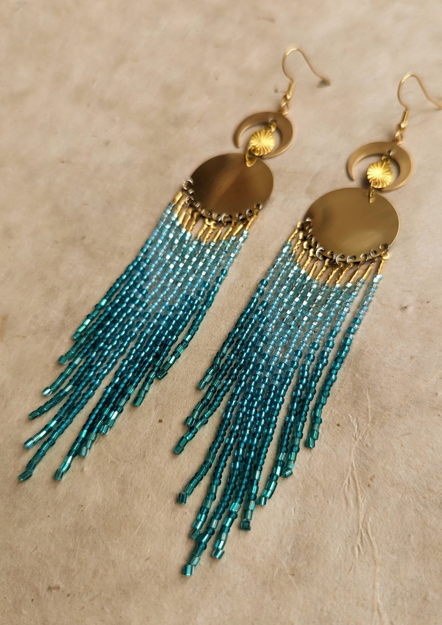 Handcrafted aqua beaded earrings by Moon & Milk, featuring cascading glass beads in shades of blue and brass accents, reflecting the beauty of the sea.