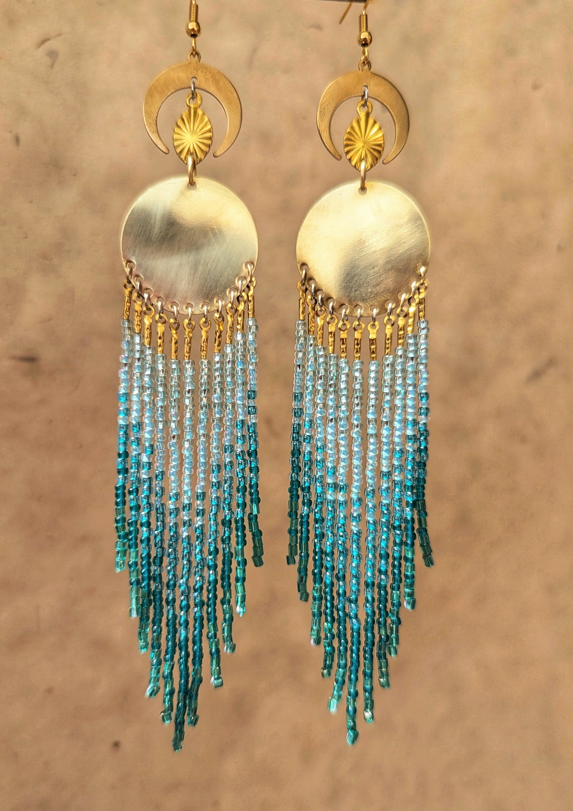 Handcrafted aqua beaded earrings by Moon & Milk, featuring cascading glass beads in shades of blue and brass accents, reflecting the beauty of the sea.