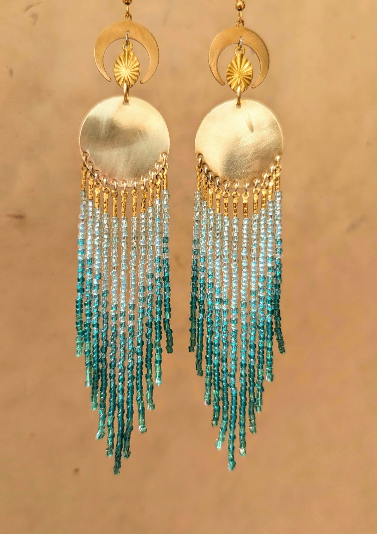 Handcrafted aqua beaded earrings by Moon & Milk, featuring cascading glass beads in shades of blue and brass accents, reflecting the beauty of the sea.