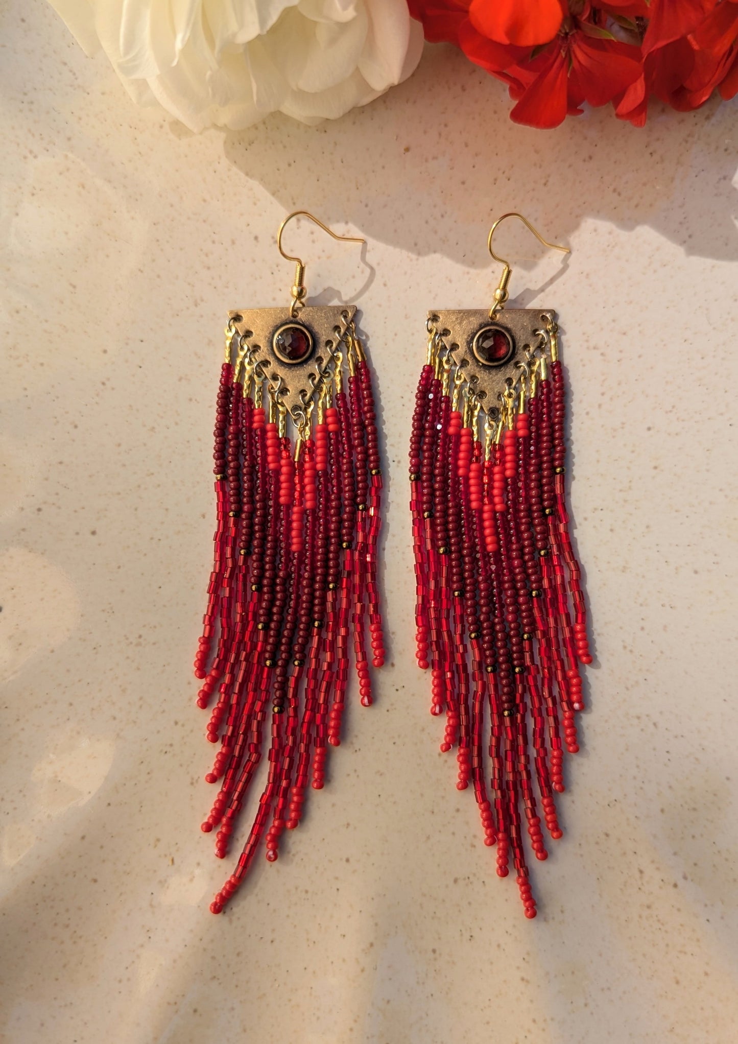 Handcrafted beaded earrings by Moon & Milk, featuring red Czech beads, brass accents, and a garnet centerpiece, showcasing intricate beadwork and artistic design.