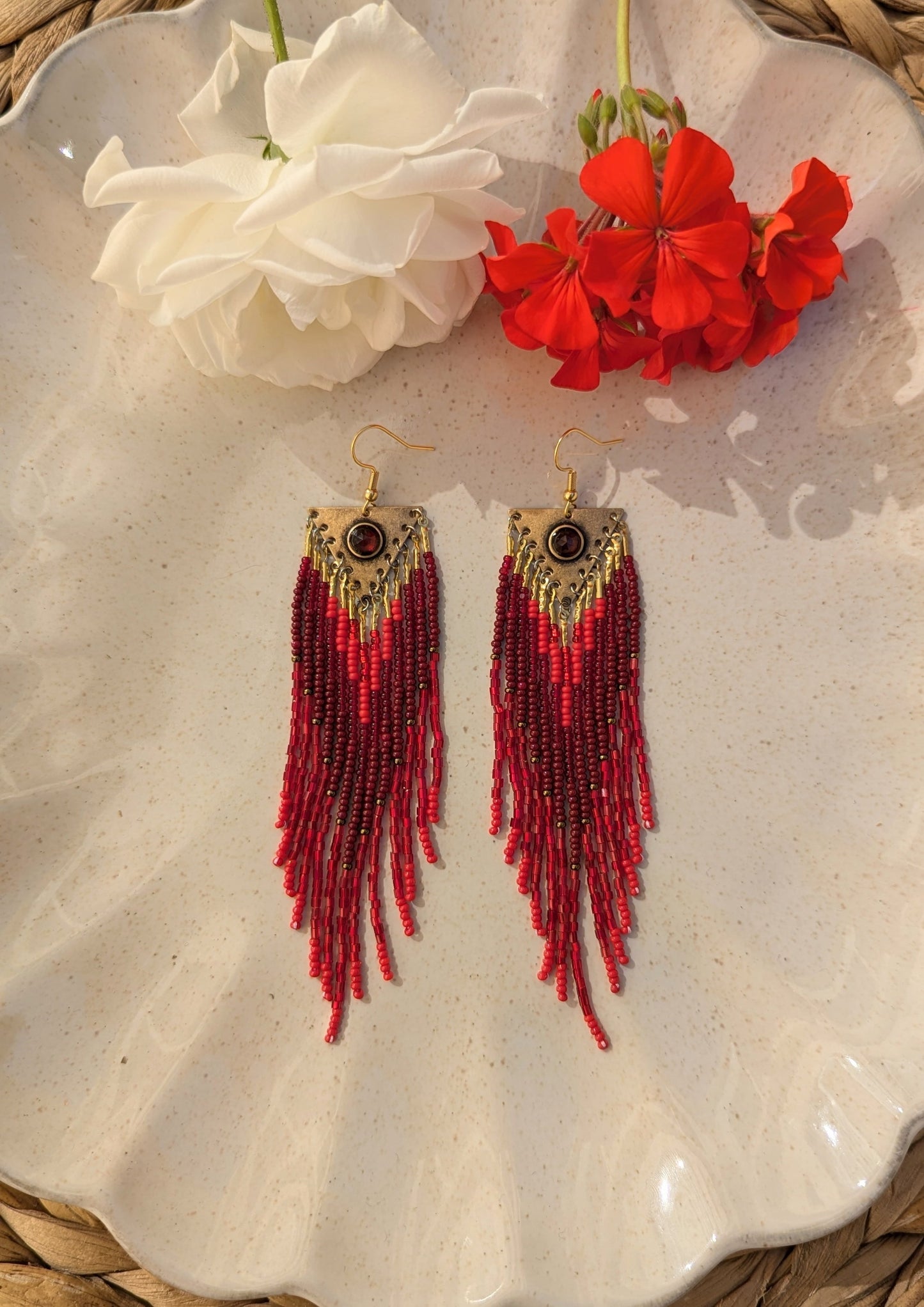 Handcrafted beaded earrings by Moon & Milk, featuring red Czech beads, brass accents, and a garnet centerpiece, showcasing intricate beadwork and artistic design.