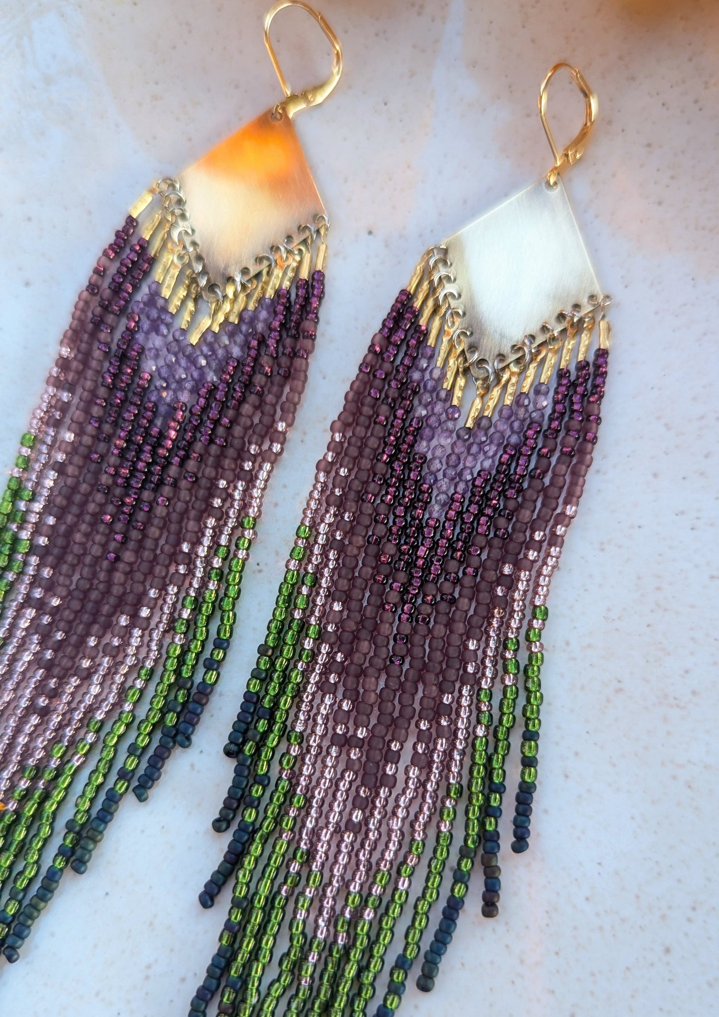 Moon & Milk handcrafted beaded earrings with purple, green, and navy glass beads, brass tops, and long fringe, designed as artisan wearable art.