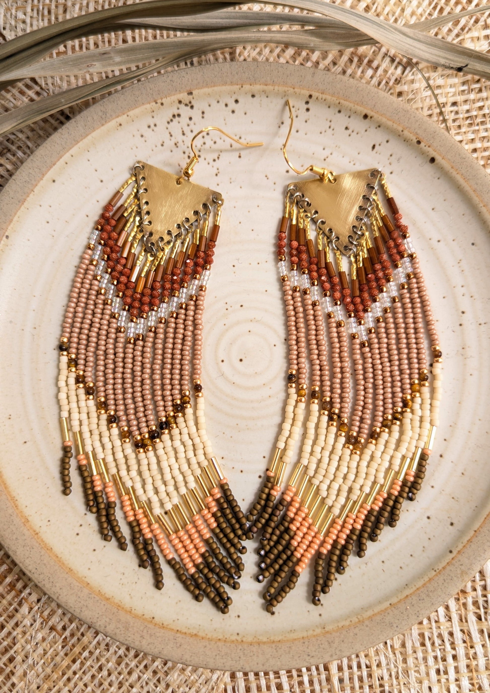 Long handcrafted fringe earrings by Moon & Milk with warm terracotta, beige, and ivory seed beads, finished with brass triangle tops and fine detailing.