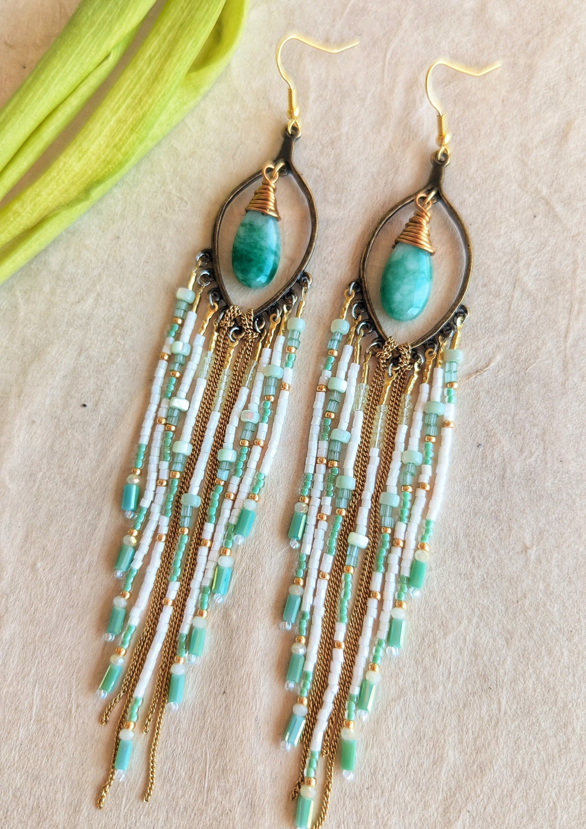 Moon & Milk mint green beaded earrings with long white, gold, and aqua fringe, featuring tear-shaped jade stones wrapped in gold brass wire.