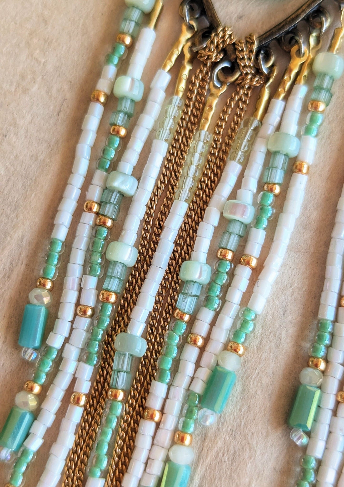 Moon & Milk mint green beaded earrings with long white, gold, and aqua fringe, featuring tear-shaped jade stones wrapped in gold brass wire.