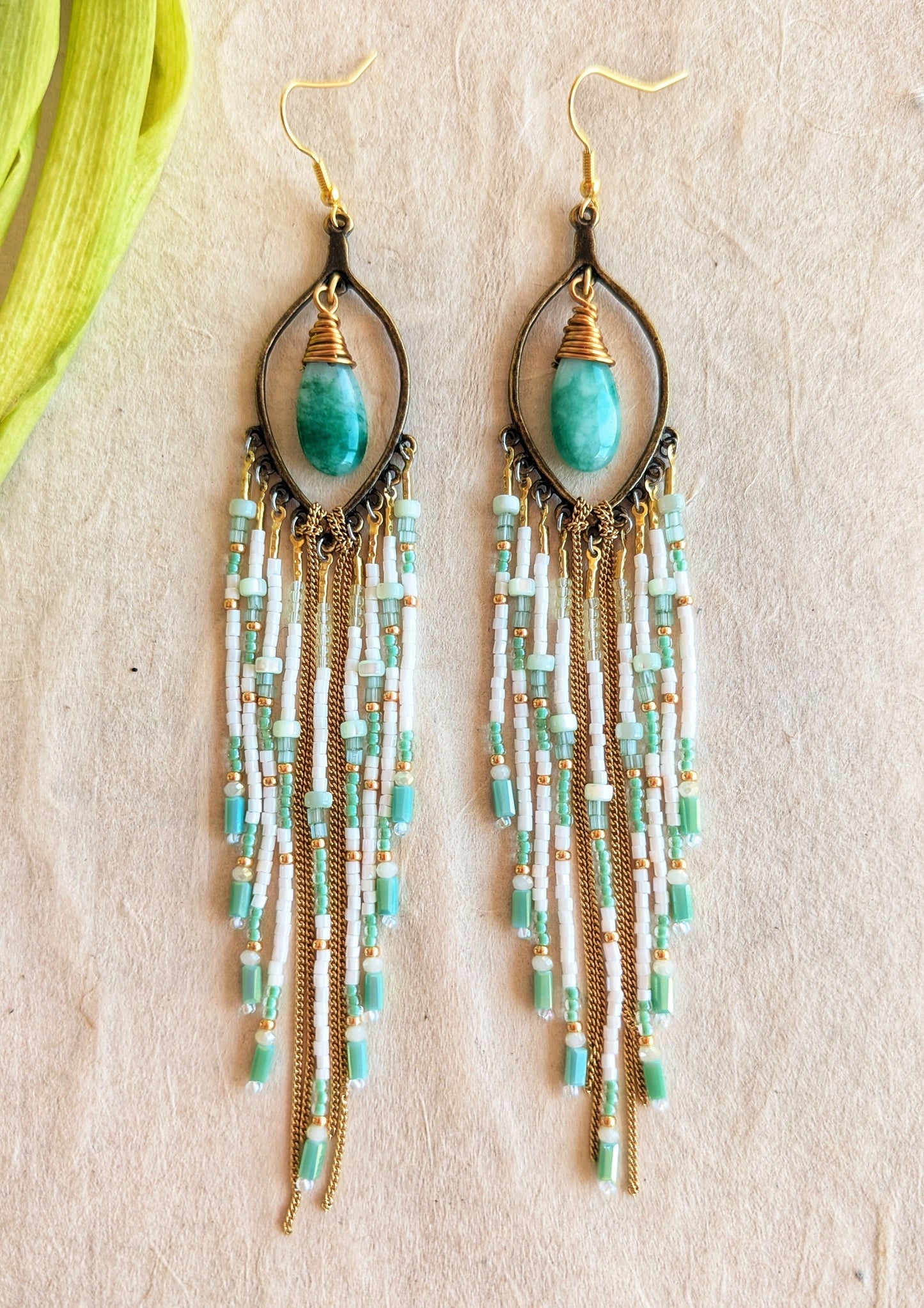 Moon & Milk mint green beaded earrings with long white, gold, and aqua fringe, featuring tear-shaped jade stones wrapped in gold brass wire.