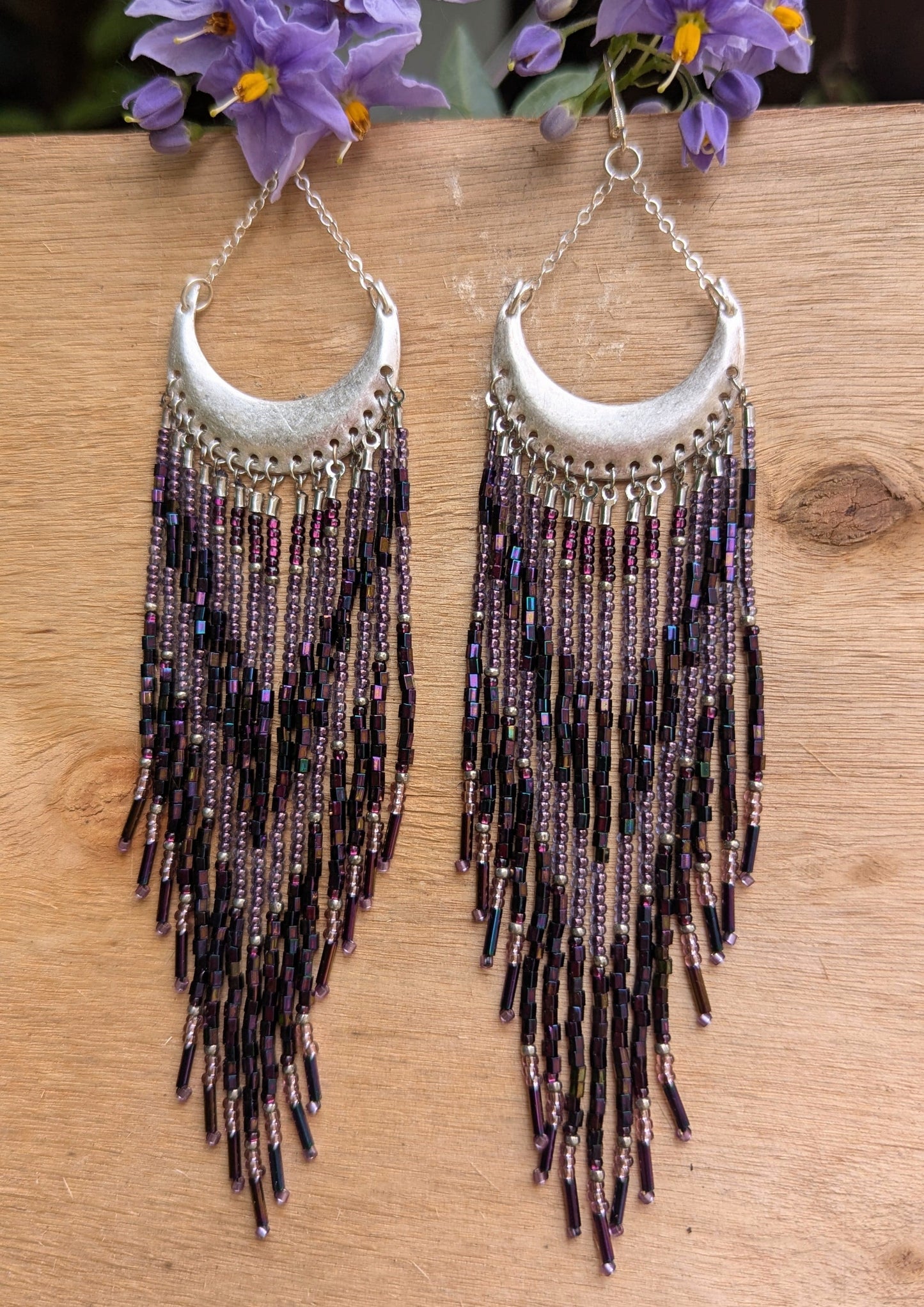 Moon & Milk crescent-shaped statement earrings with cascading purple, amethyst, and metallic seed beads and bugle beads on silver half-moon findings.