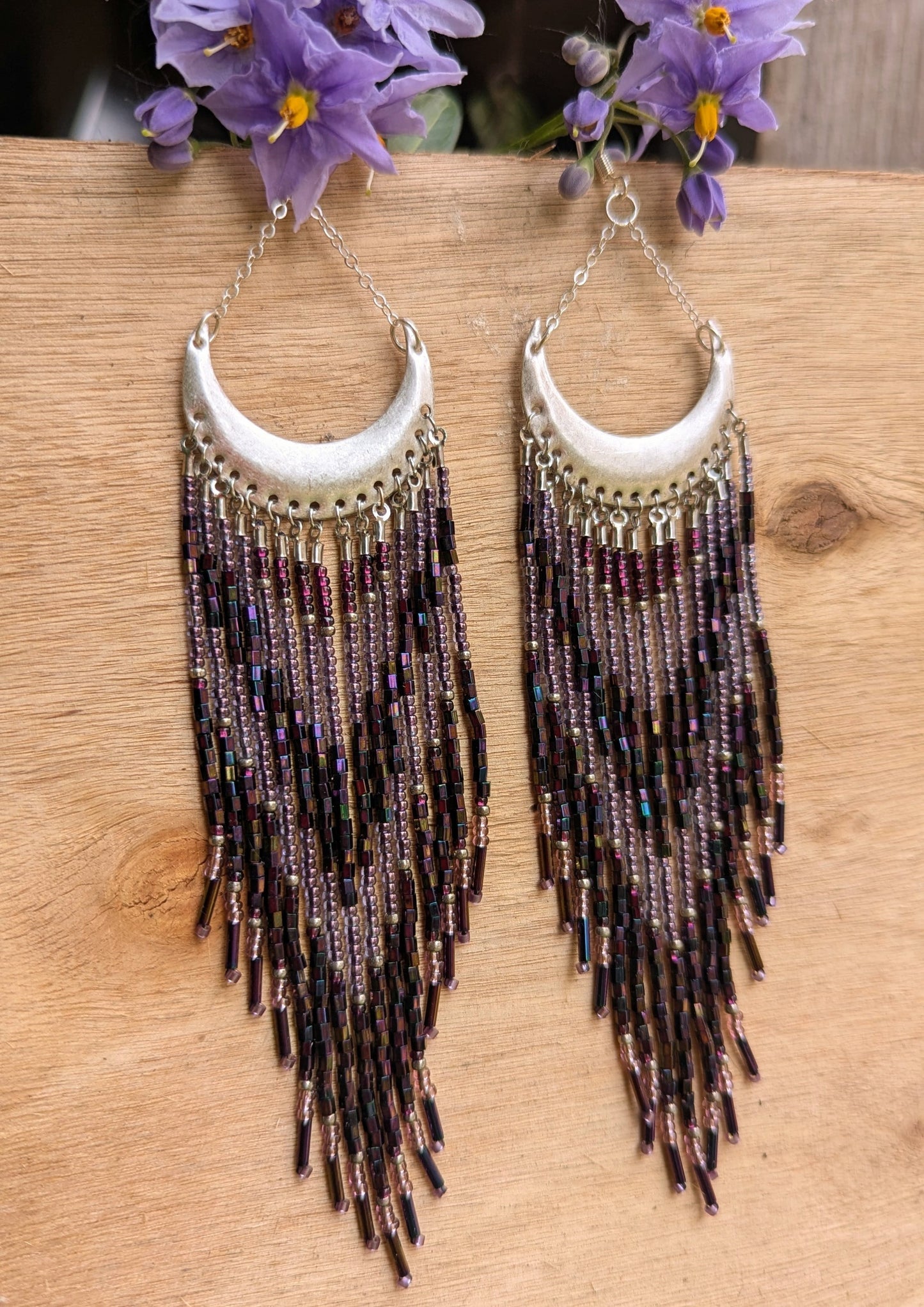 Moon & Milk crescent-shaped statement earrings with cascading purple, amethyst, and metallic seed beads and bugle beads on silver half-moon findings.