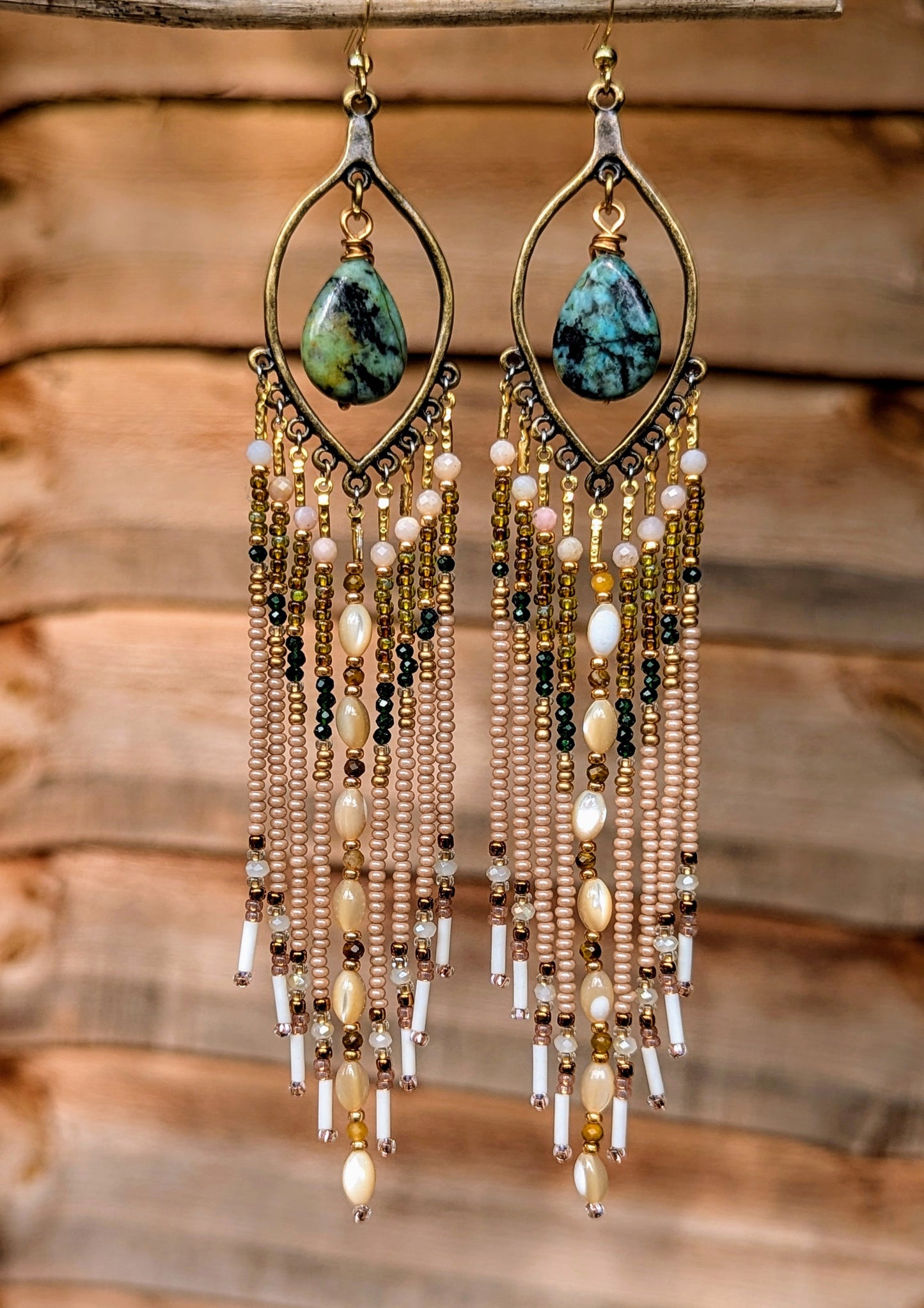 Hand-beaded earrings with turquoise stones on a wooden background.