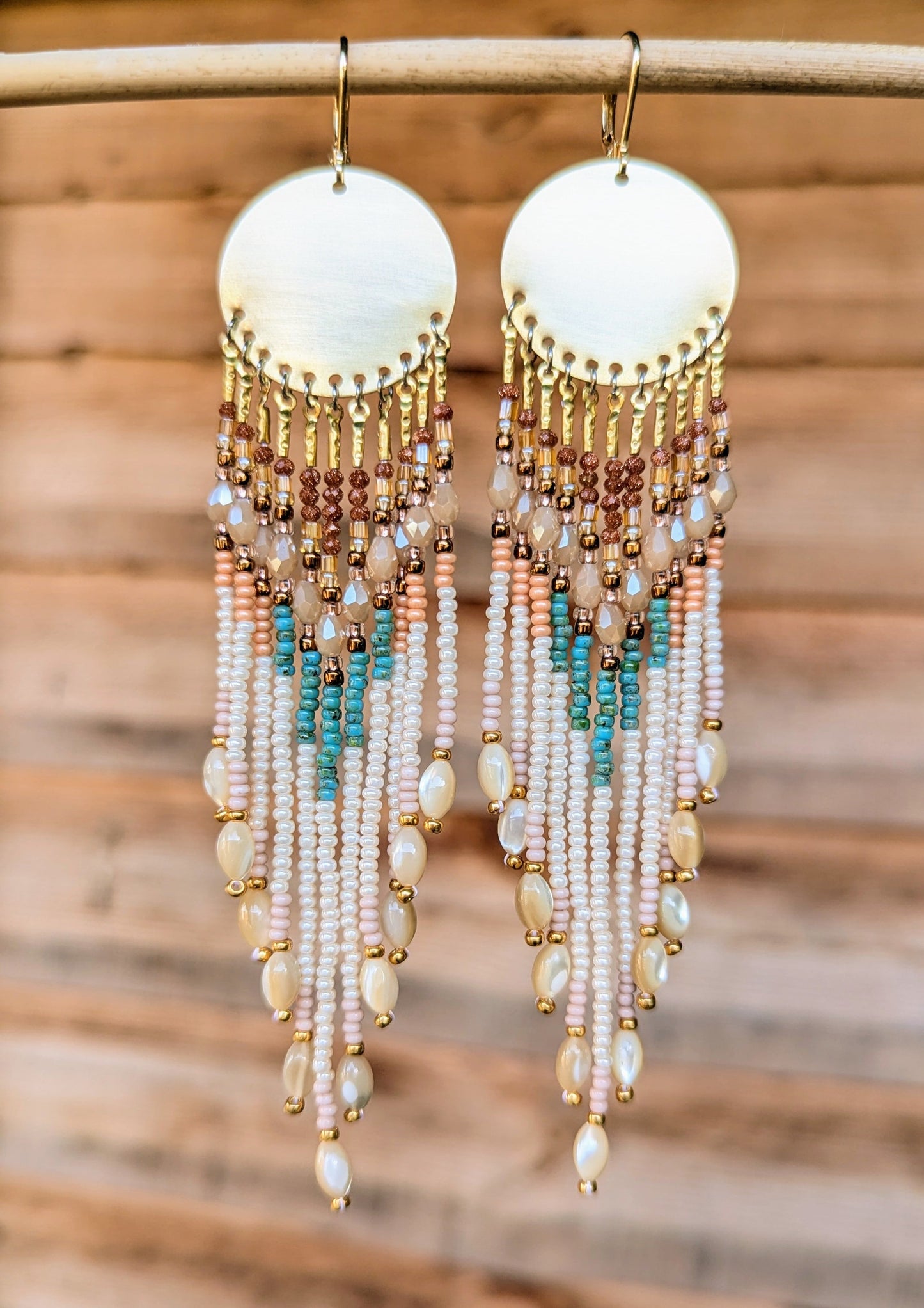 Hand-beaded earrings with gold, turquoise, and pearl-like beads on a wooden background by Moon & Milk.