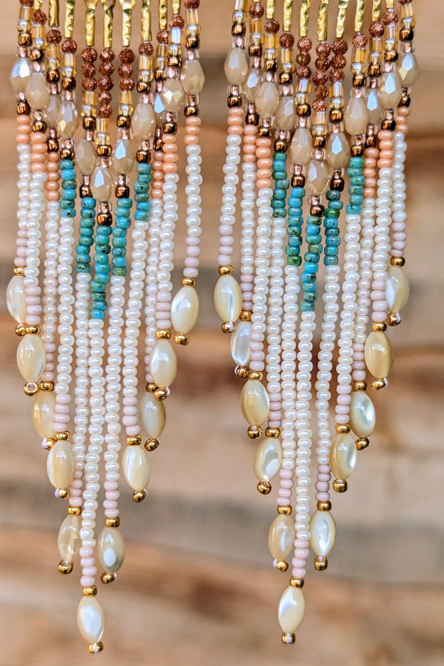 Multicolored handcrafted beaded earrings with pearls on a blurred background.