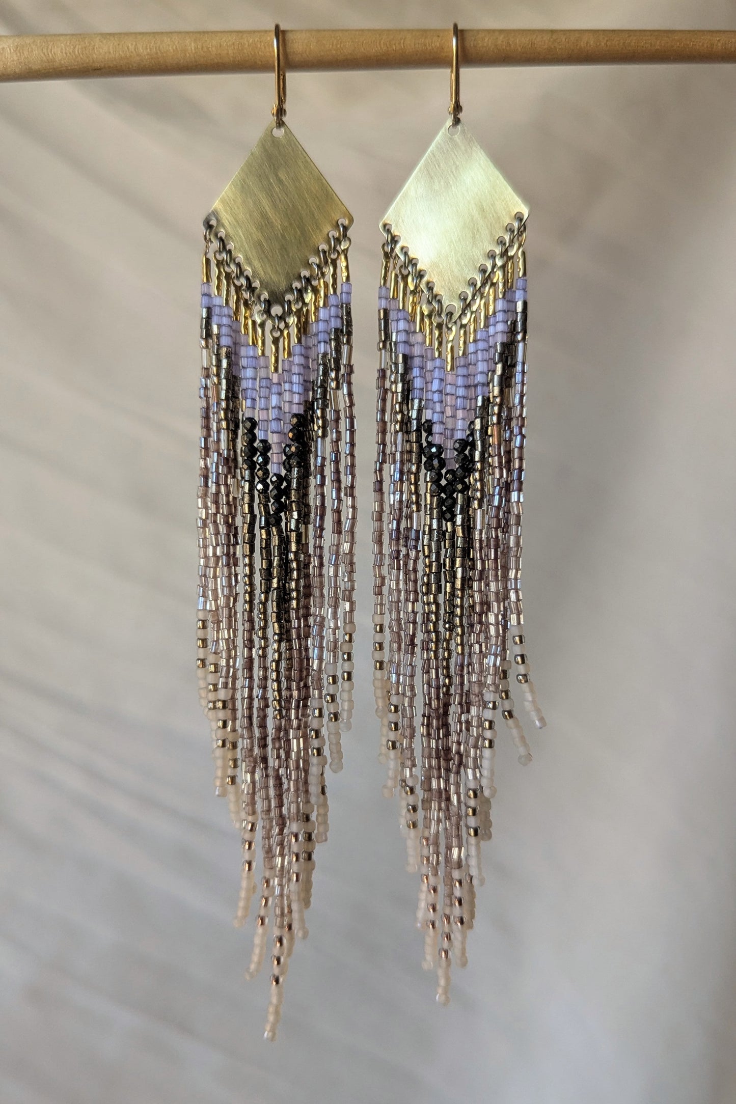Beaded fringe earrings on a neutral background.