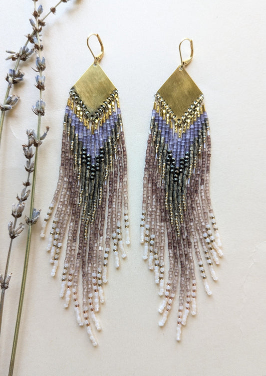 Long beaded earrings with metallic accents on a neutral background.