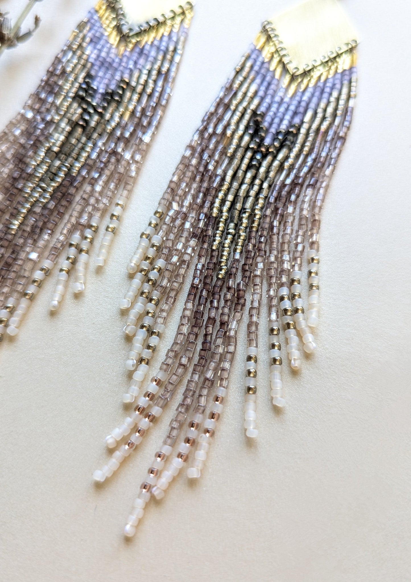 Beaded earrings with a gradient of colors on a light background.