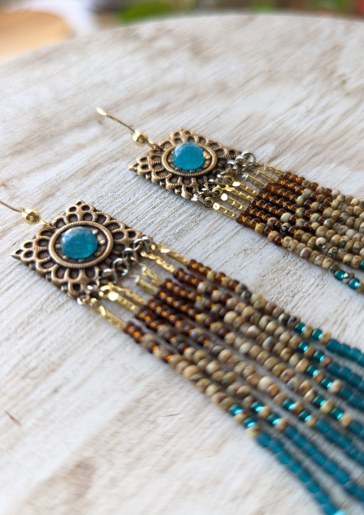 Pair of beaded earrings with apatite stones on a textured surface.
