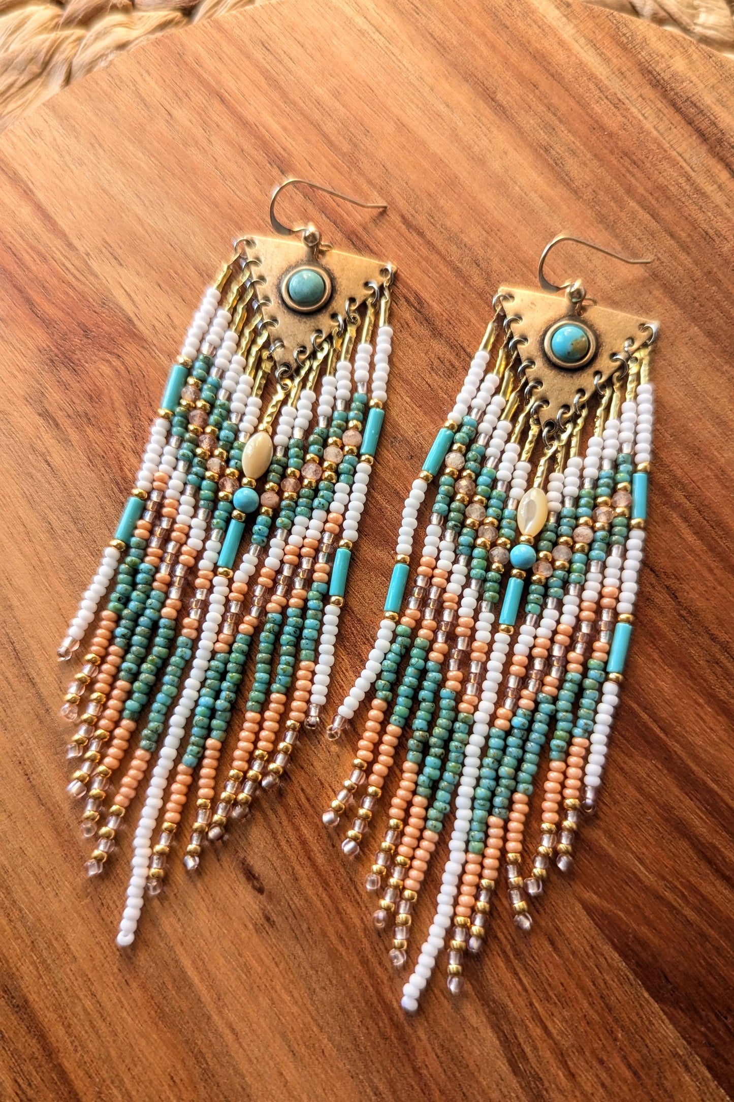 Beaded earrings with turquoise and gold accents on a wooden surface by Moon & Milk.