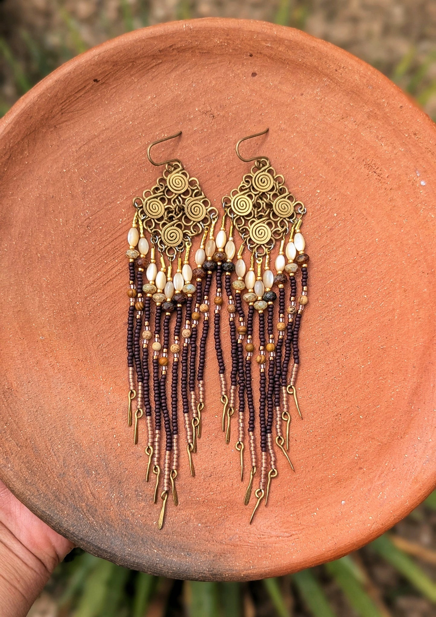 Pair of beaded earrings on a terracotta plate with a natural background