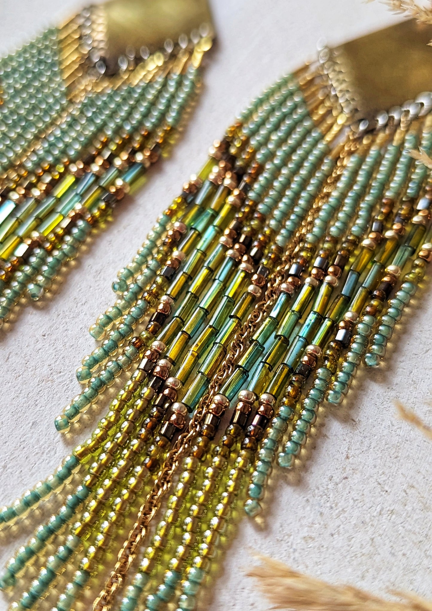 Beaded earrings with olive green, gold, and soft blue tones, featuring brass diamond tops and gold chain fringe, on a white background by Moon & Milk.