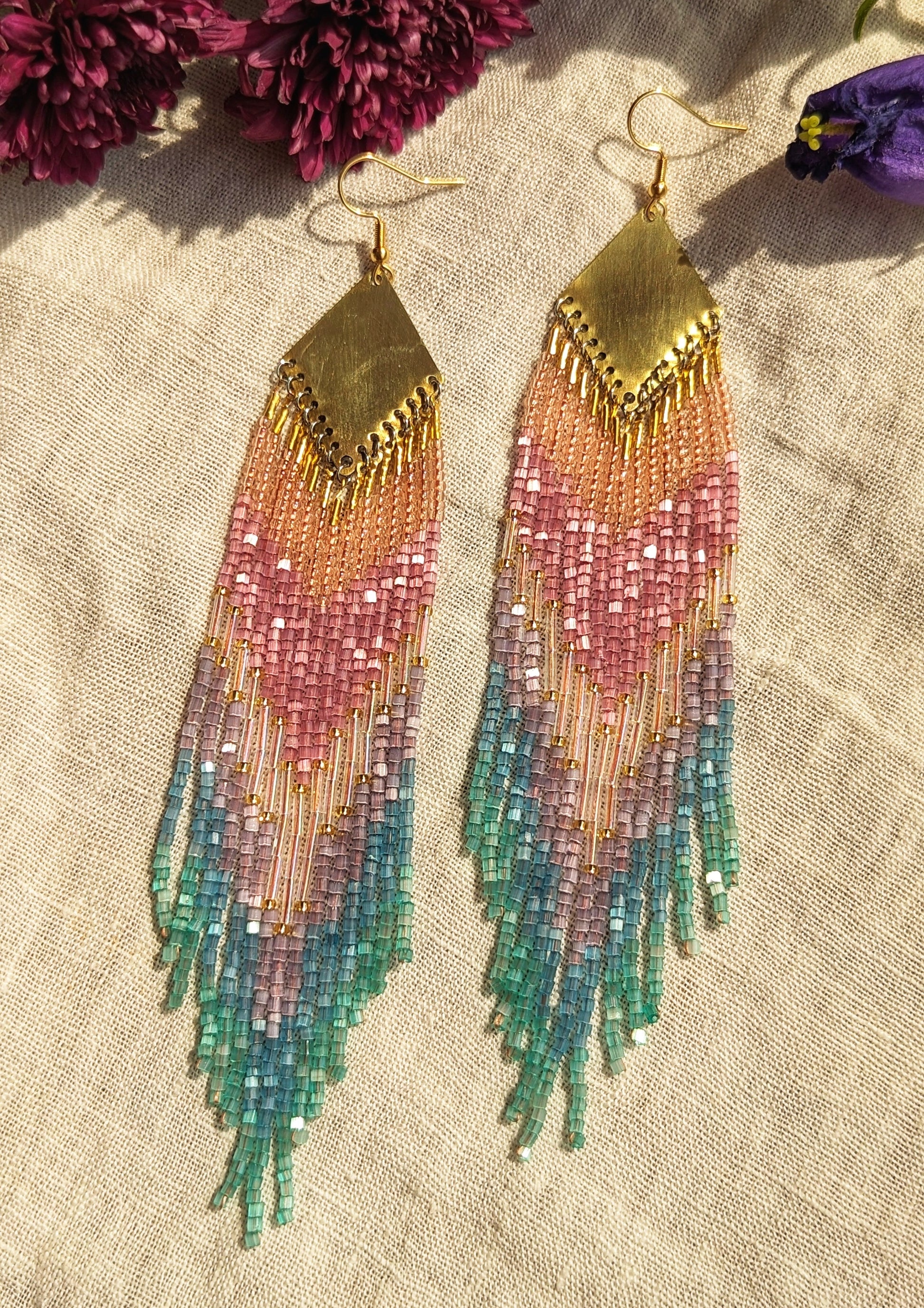 Moon & Milk handcrafted beaded earrings with a gradient of pink, purple, and teal beads, finished with gold-tone brass findings with an artisan design.