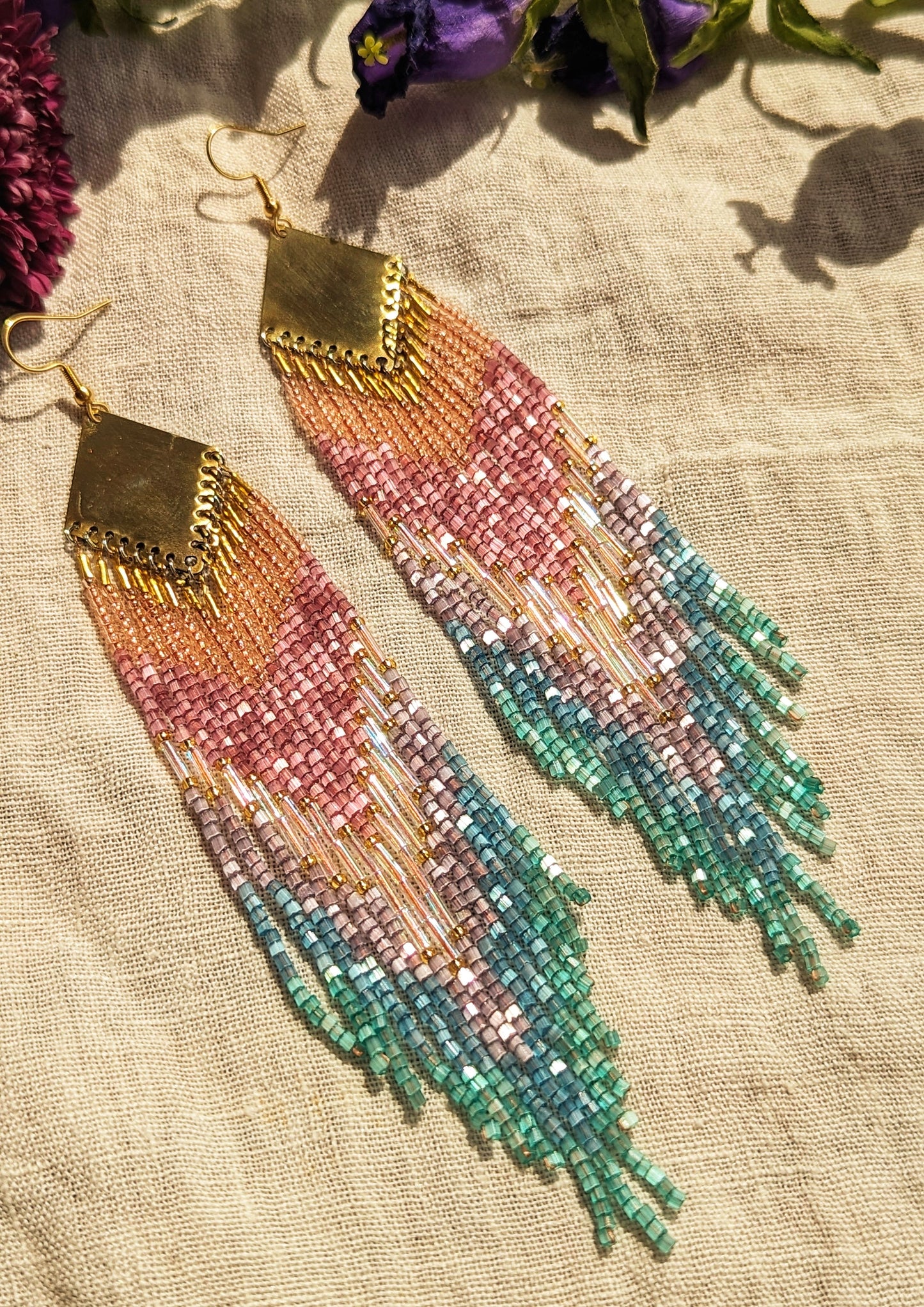 Moon & Milk handcrafted beaded earrings with a gradient of pink, purple, and teal beads, finished with gold-tone brass findings with an artisan design.