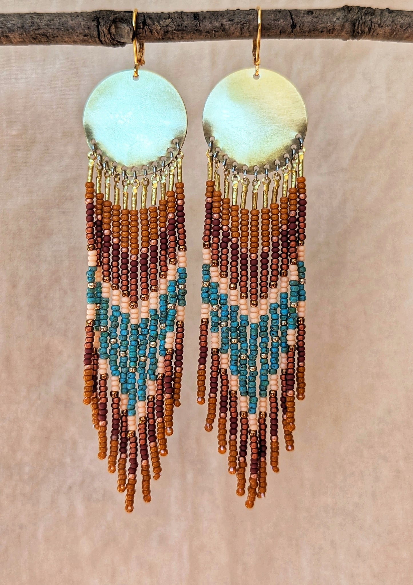 Moon & Milk handmade earrings with brown, turquoise, and peach seed beads hanging from round brass discs.