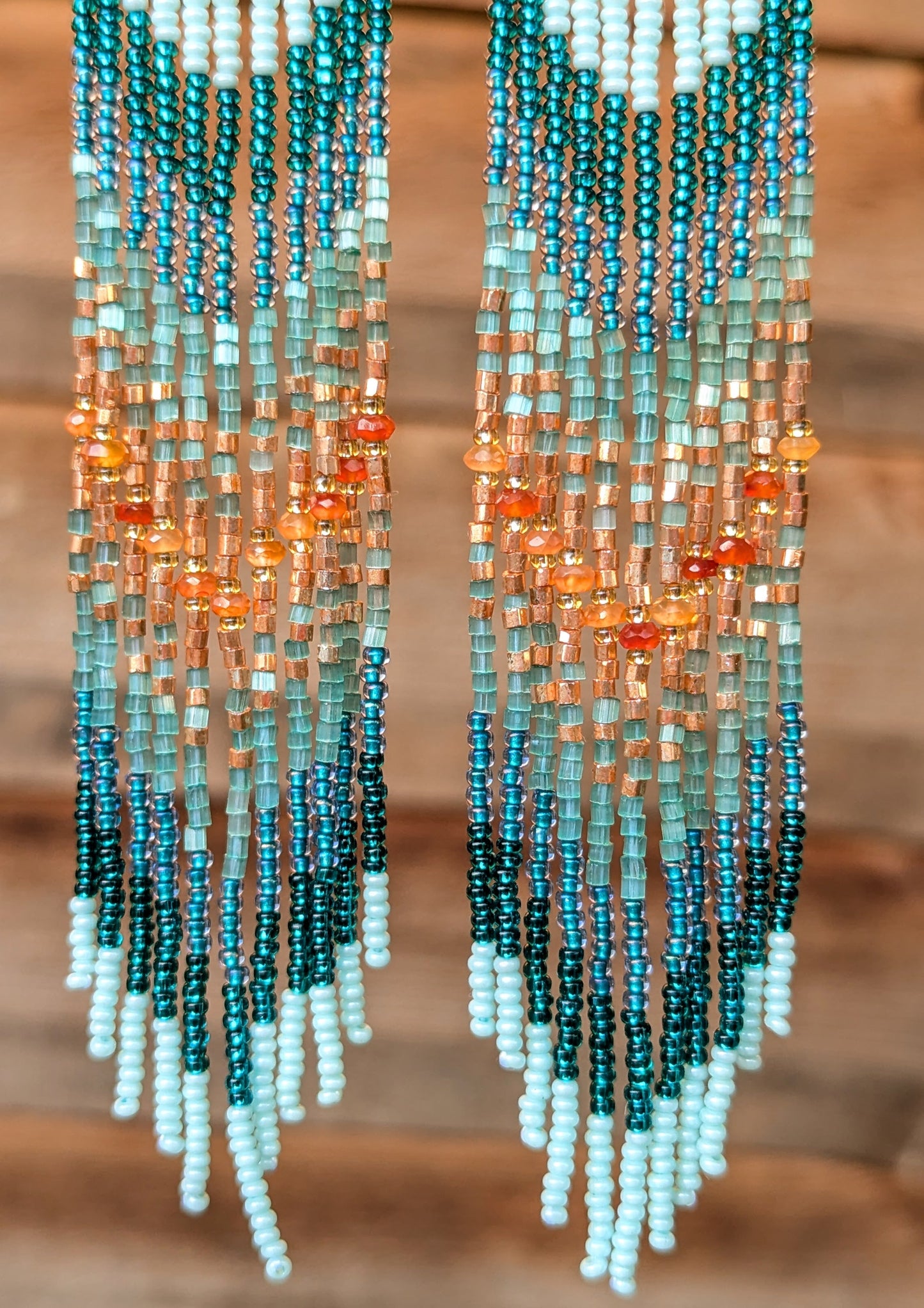 Beaded earrings with a gradient of colors on a wooden background