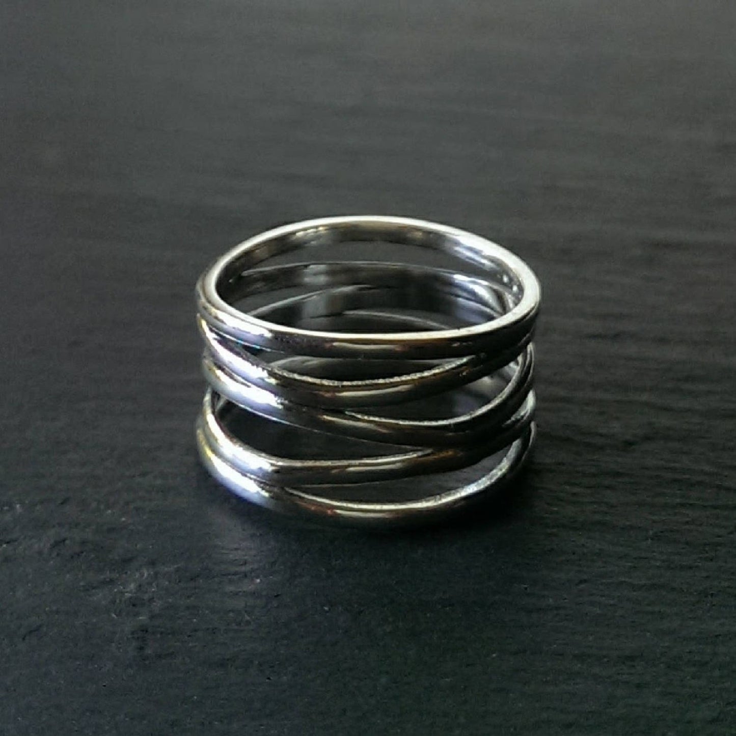 Sterling silver multi-band ring on a dark gray background.