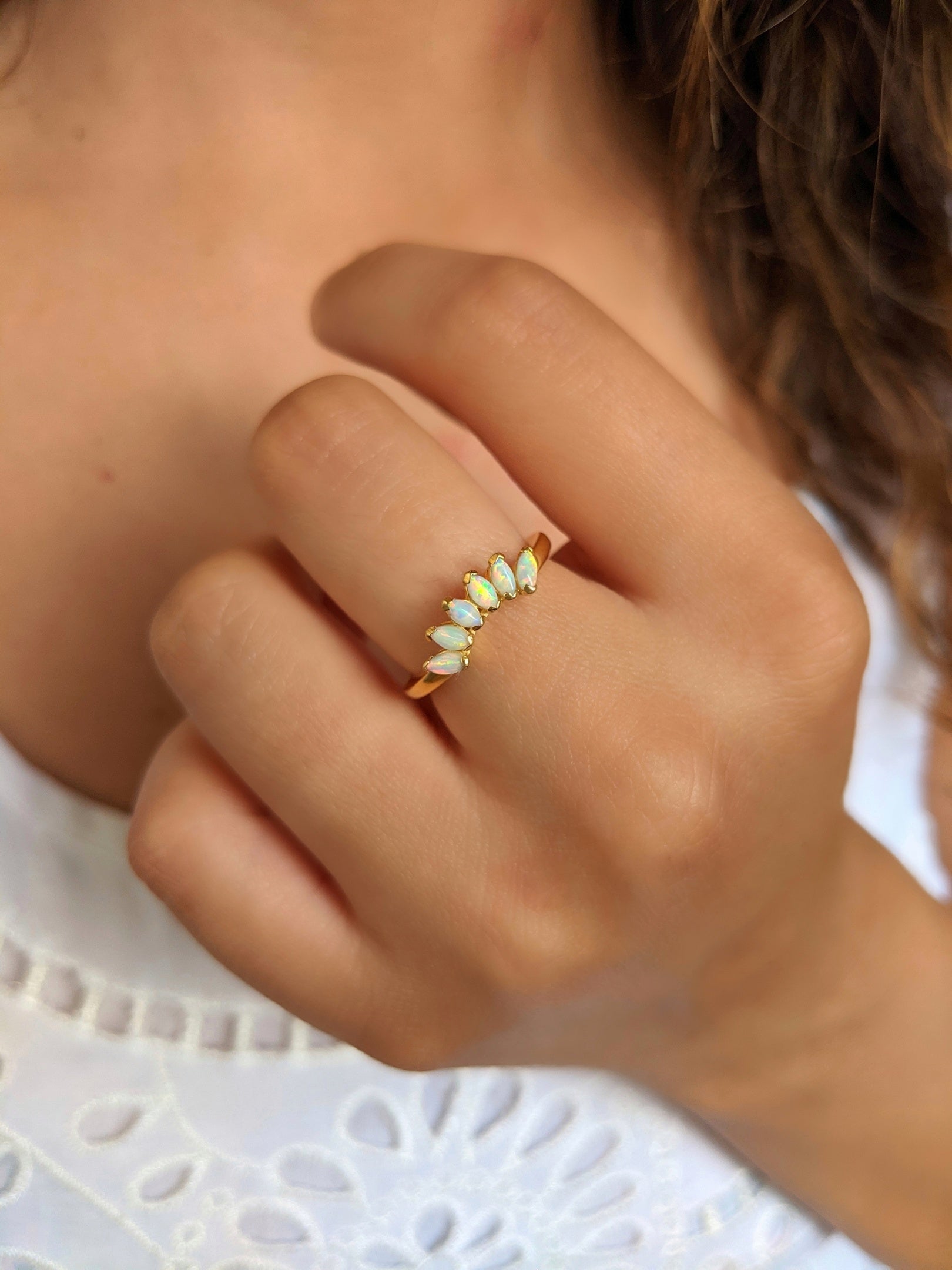 Gold-plated opal ring with marquise stones in the center and CZ side accents, worn on a hand with natural lighting.